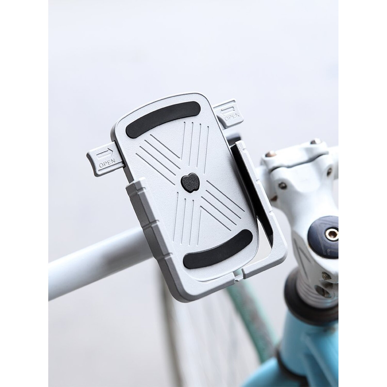 Silberner Telefonhalter an einem Fahrradlenker befestigt, mit einem weißen und blauen Fahrrad im Hintergrund.