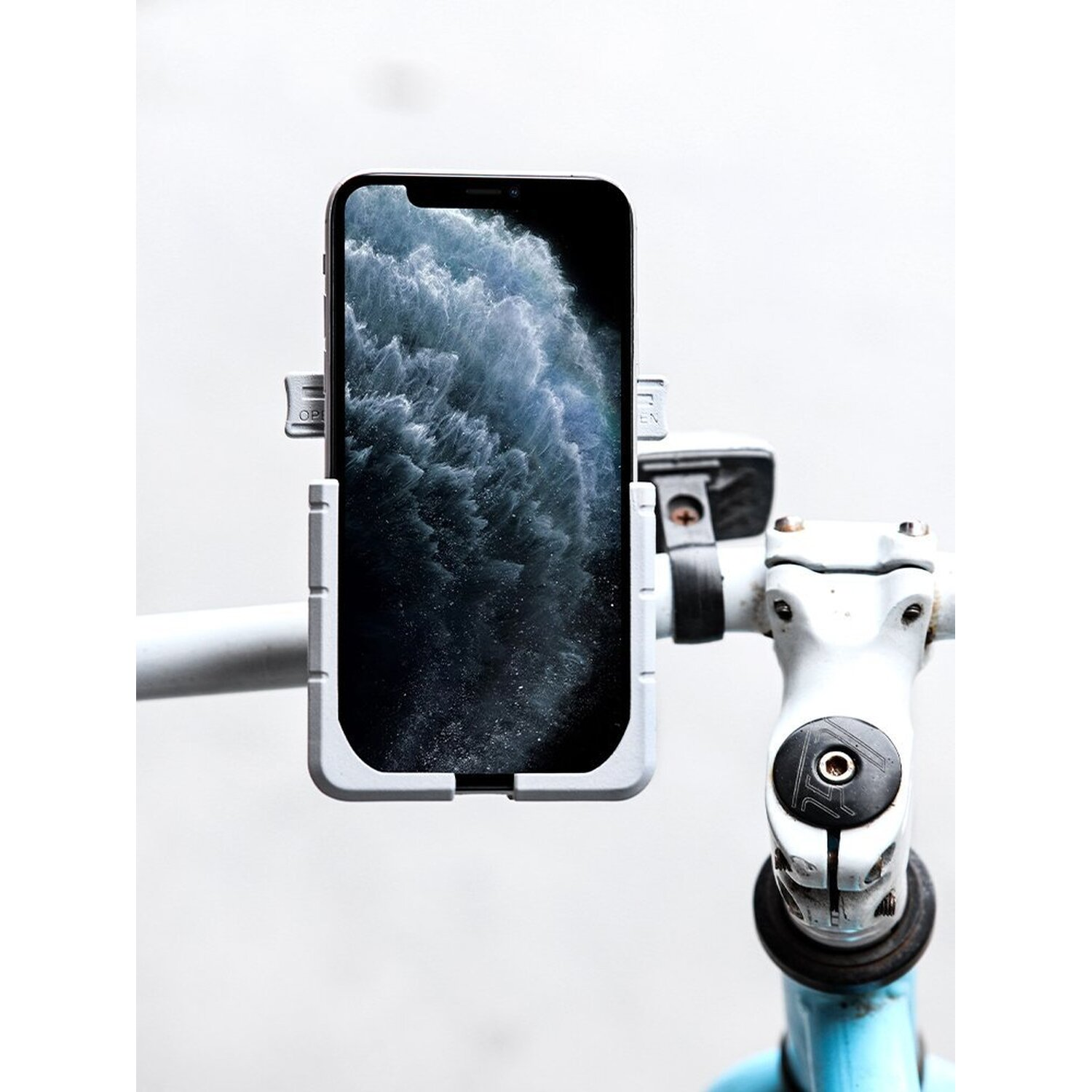 Ein Telefon ist an einem Fahrradlenker montiert. Das Telefon befindet sich in einer grauen Halterung.