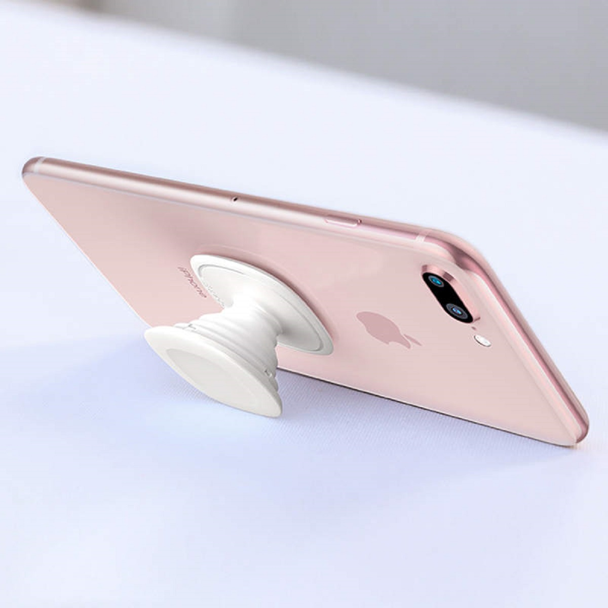 Ein Telefon mit einem weißen Ständer an der Rückseite, auf einer Oberfläche platziert. Das Telefon ist rosa.
