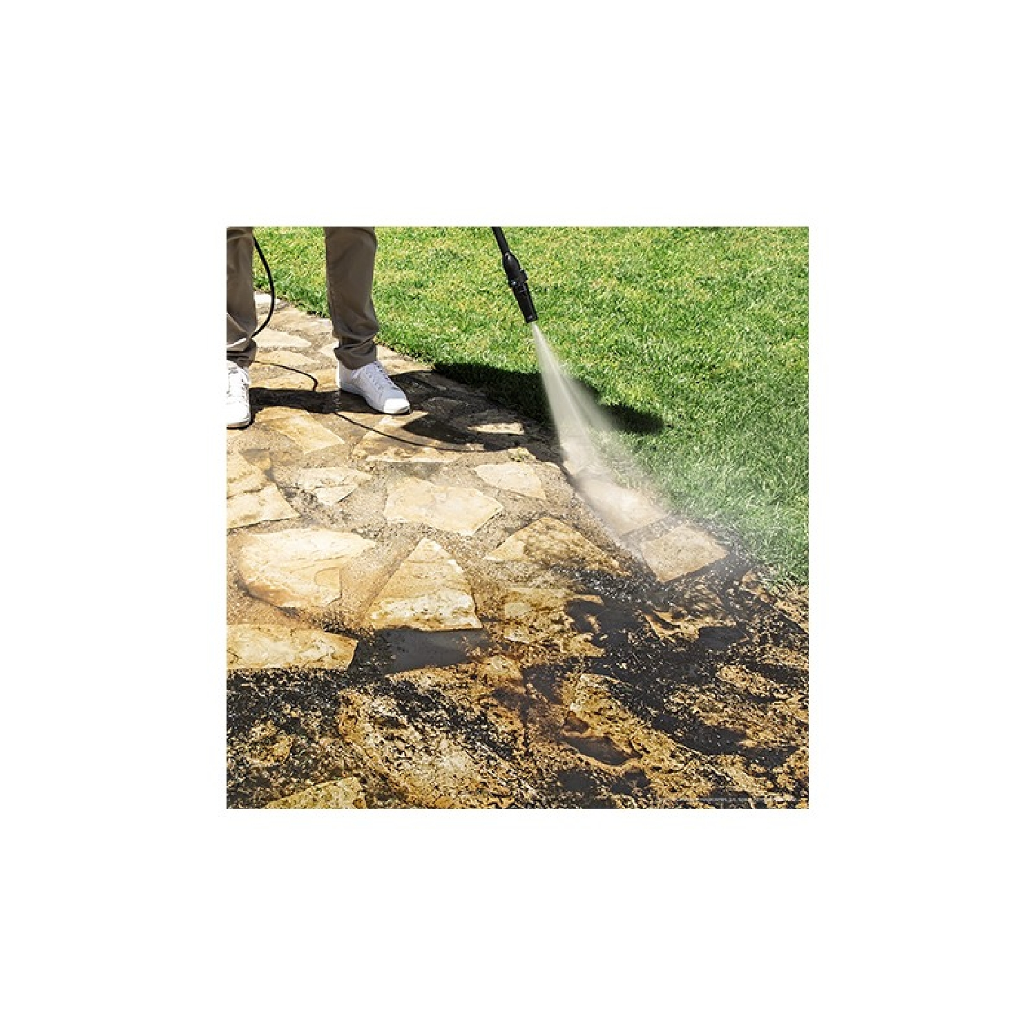 Persona lavando con agua a presión un patio de piedra, rociando agua. Fondo: hierba verde.