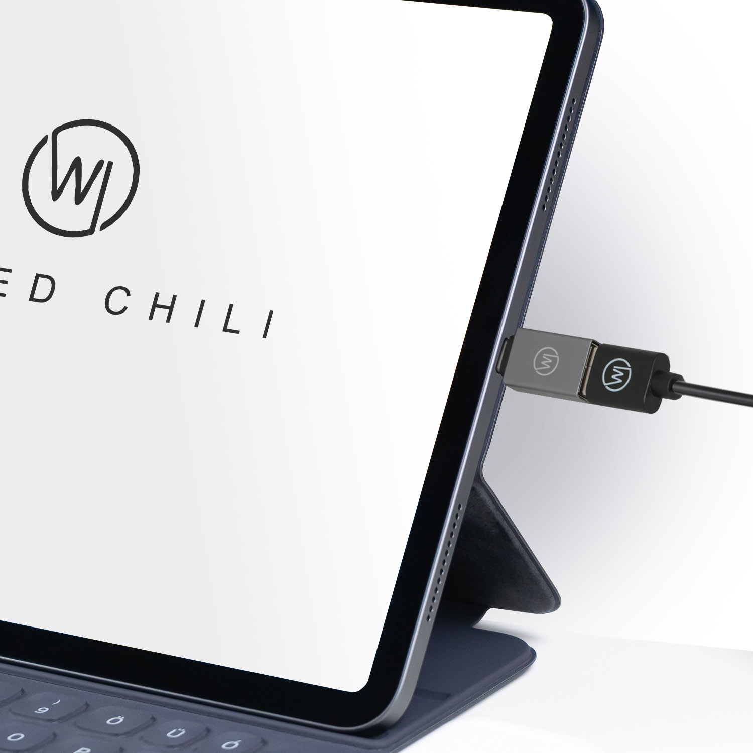 Tablet mit Ladeanschluss. Ladegerät ist angeschlossen. Der Bildschirm zeigt das Red Chili Logo.