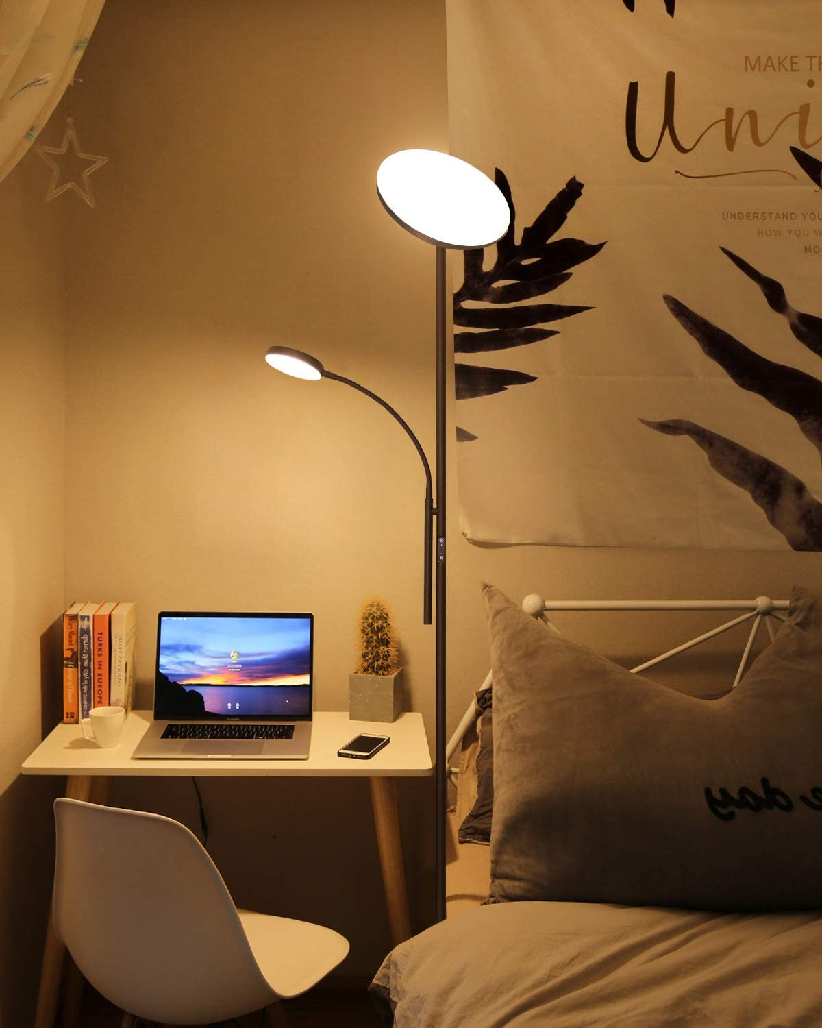 Eine Schlafzene mit Laptop, Schreibtischlampe, Büchern und einem Bett mit Poster.