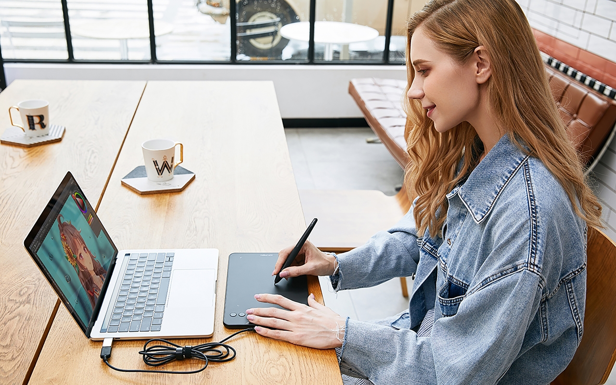 Donna che usa un laptop e una tavoletta grafica con una penna.