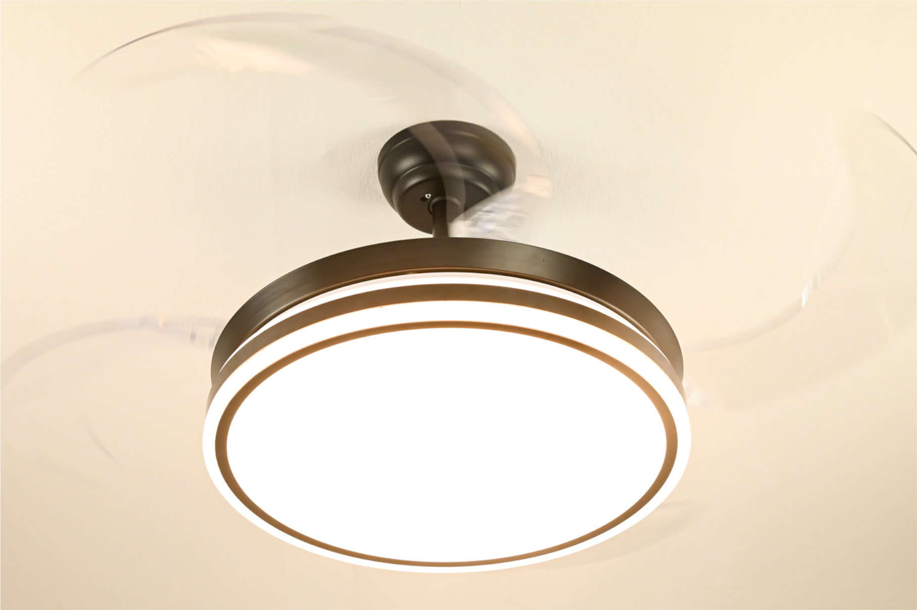 Deckenventilator mit Licht. Die Flügel sind verschwommen. Das Licht ist hellweiß.