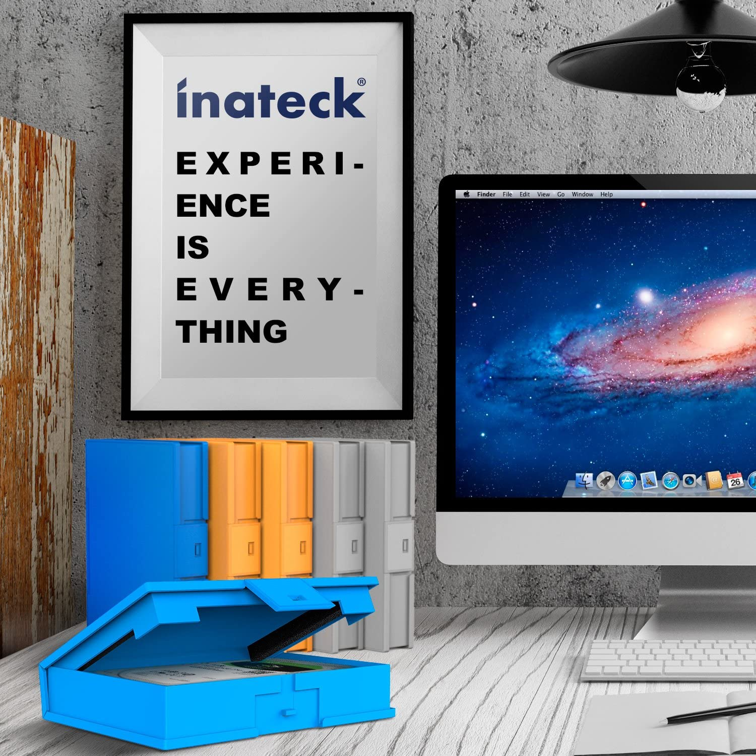 Schreibtisch mit Monitor, Poster mit "EXPERIENCE IS EVERYTHING" und Aufbewahrungsboxen. Blau, orange und grau.