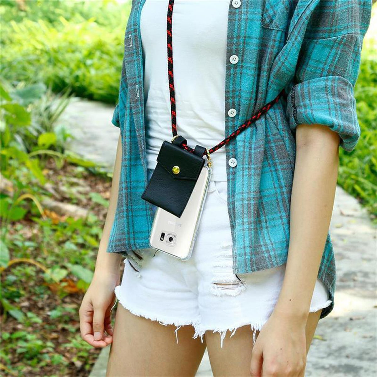 Donna con top bianco, camicia a quadri blu, pantaloncini bianchi, con custodia per telefono. Il background è un parco.