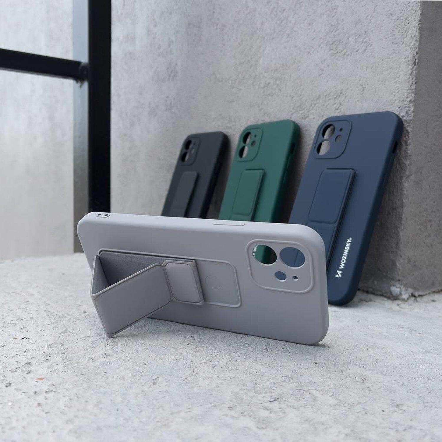 Vier Telefonhüllen in verschiedenen Farben werden mit einem Ständer angezeigt. Grau, Grün, Blau und Schwarz.