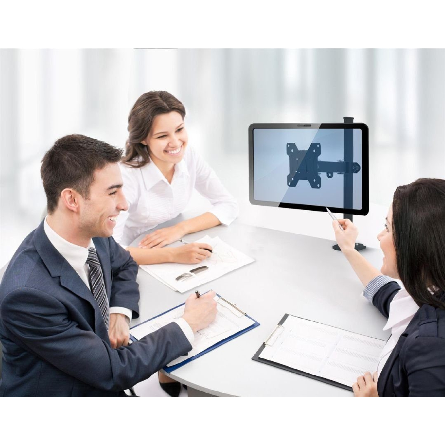 Drei Personen in einem Meeting, die auf einen an der Wand montierten Bildschirm schauen. Sie sind in einem gut beleuchteten Büro.