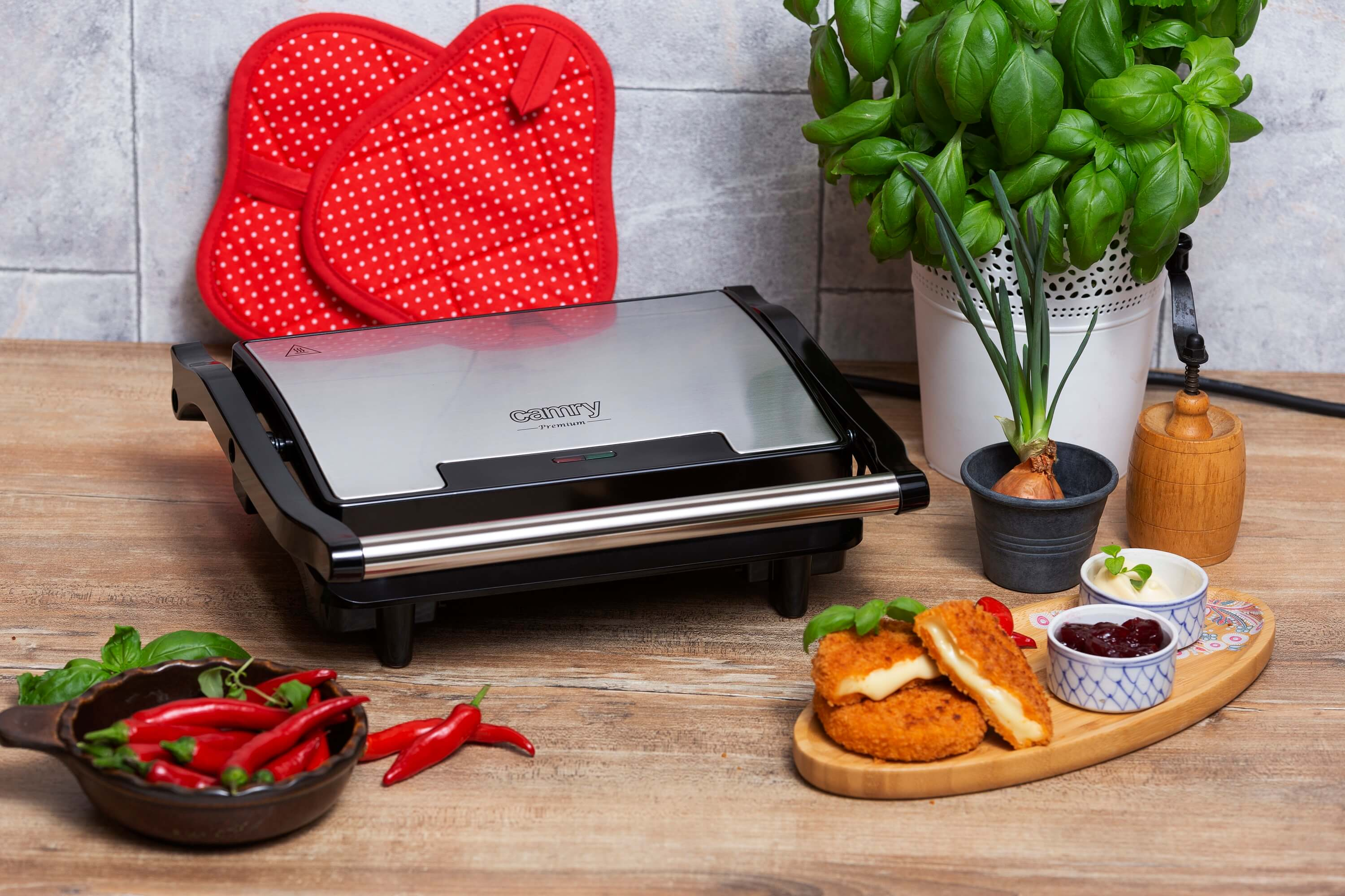 Grill Camy z jedzeniem, bazylią i czerwoną papryką na drewnianym stole.