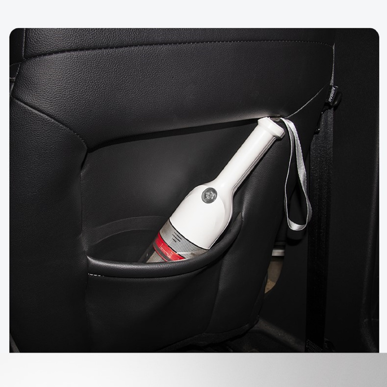 Ein weißer und roter Handstaubsauger in einer Autositz-Tasche. Schwarzer Autositz im Hintergrund.
