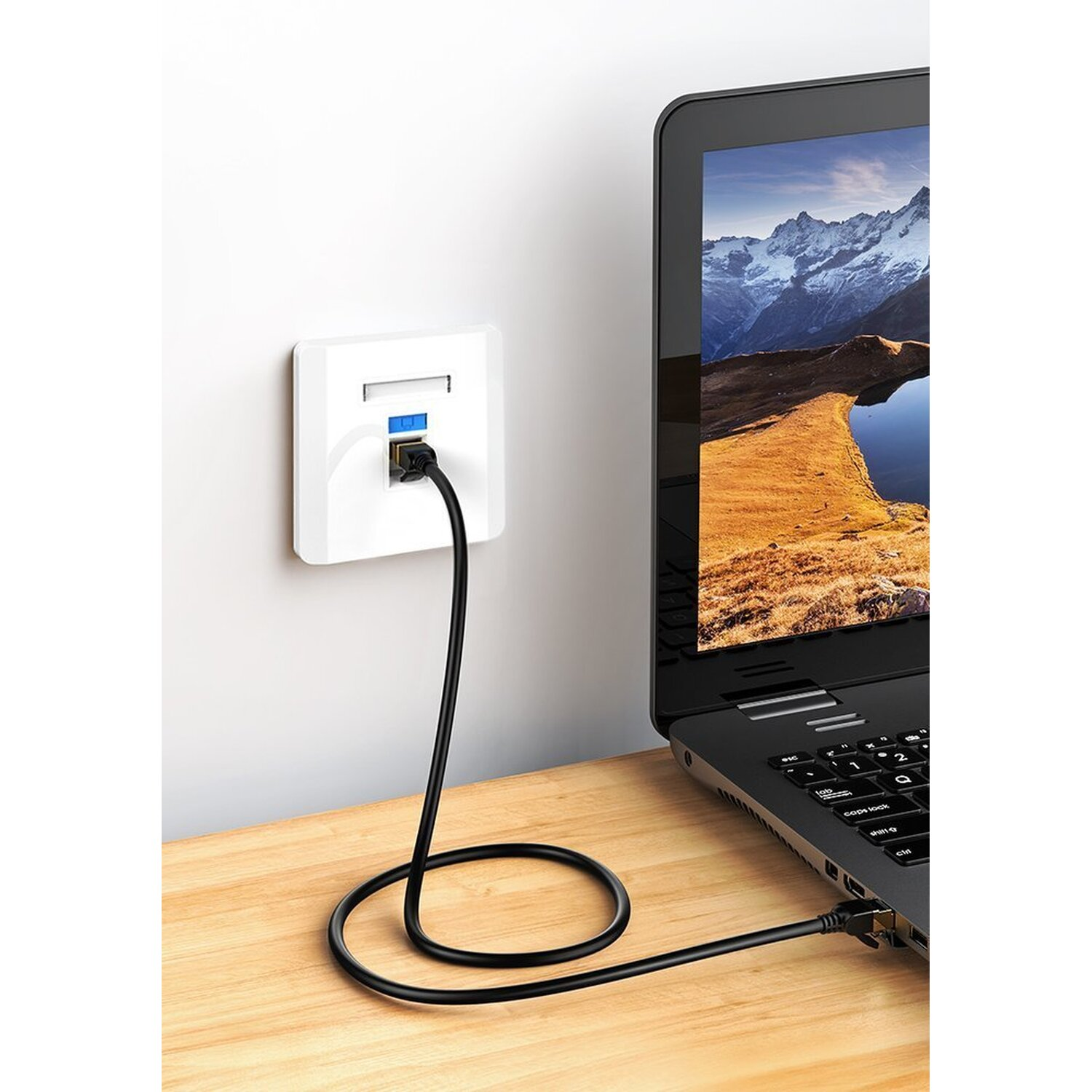 Ein Laptop, der über ein schwarzes Kabel mit einer Steckdose verbunden ist, auf einem Holztisch.