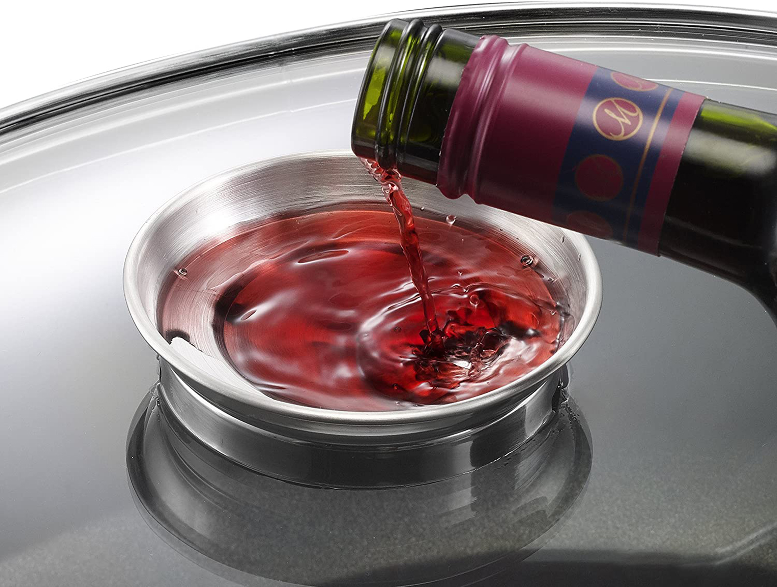 Rotwein, der in eine Edelstahlschale auf Glasfläche gegossen wird.