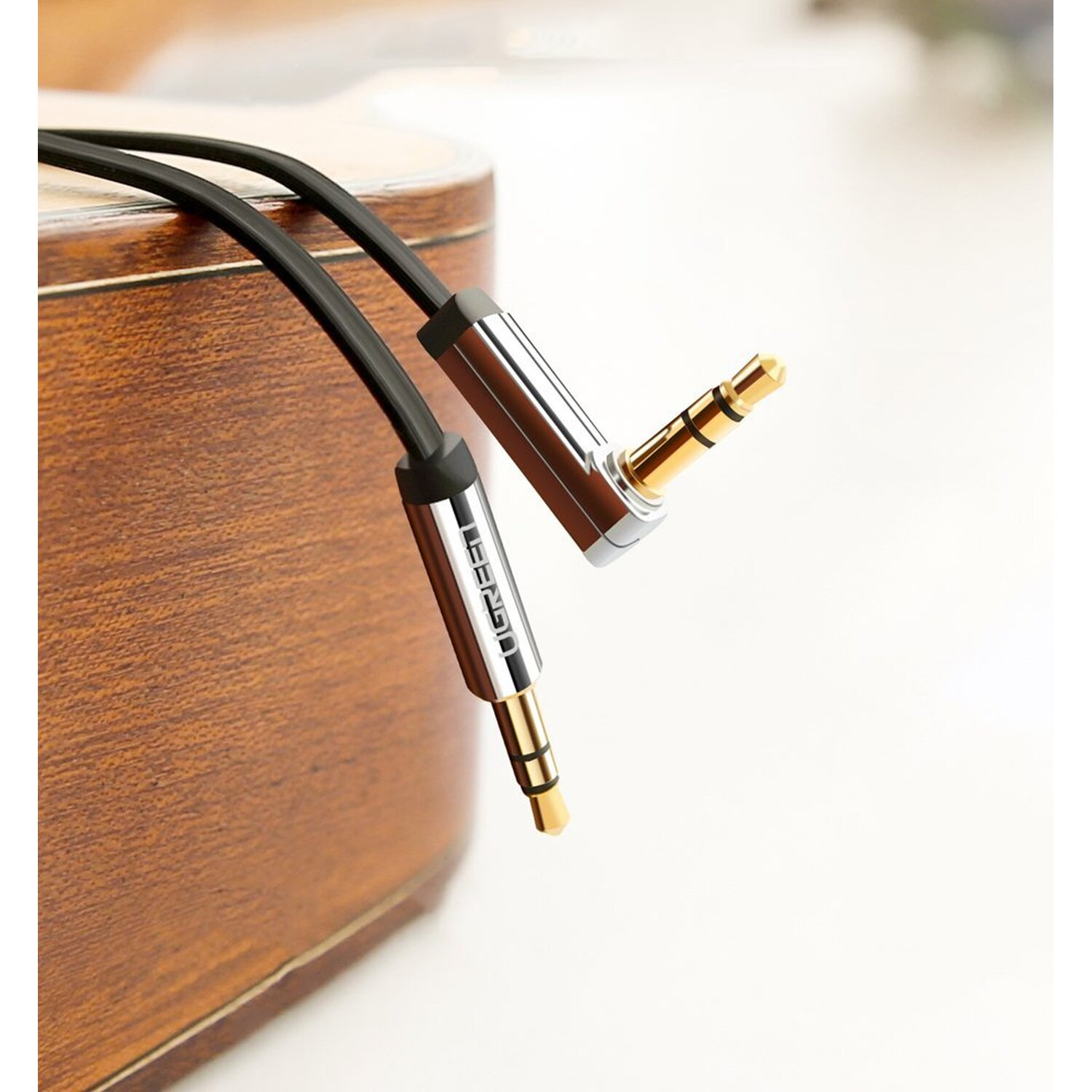 Zwei Audiokabel mit Goldsteckern auf einer Holzoberfläche.