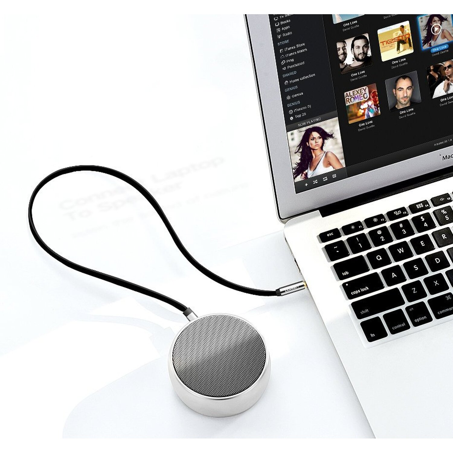 Ein silberner Lautsprecher, der an einen Laptop angeschlossen ist. Der Laptop zeigt eine Musik-Streaming-App.