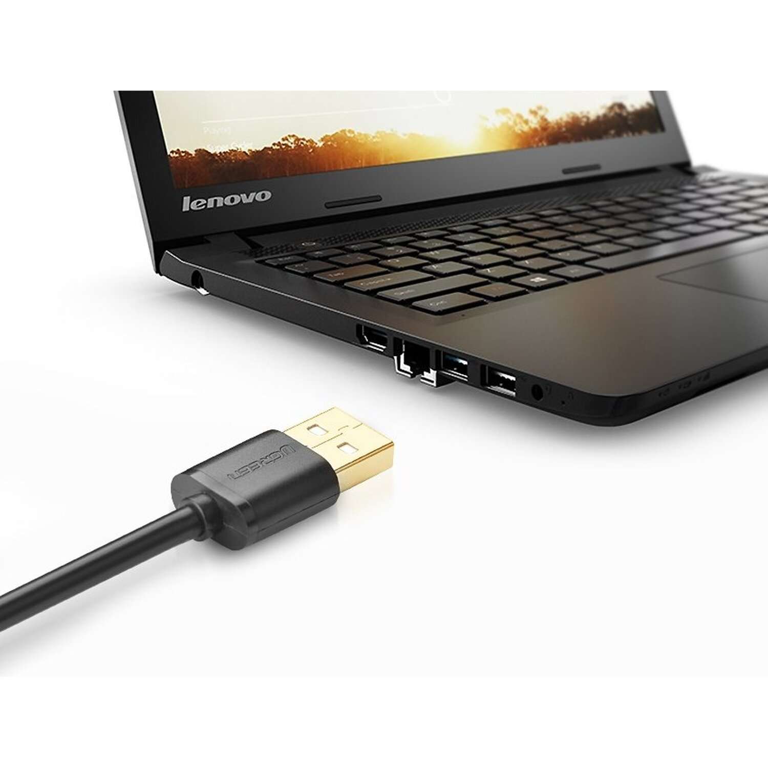 USB-kabel aangesloten op laptop. Zwarte kabel en laptop met witte achtergrond.