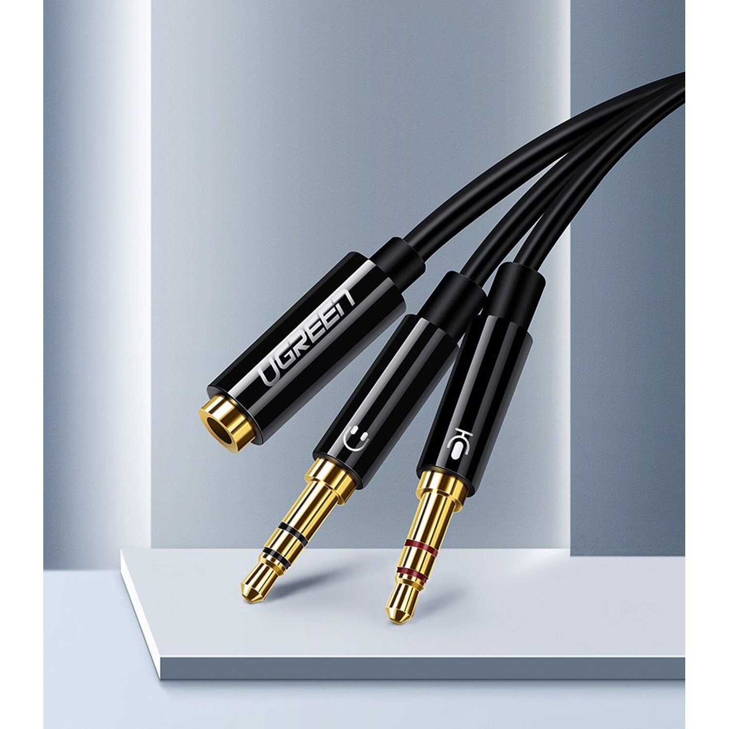 Dwa czarne i złote kable audio z wtyczkami 3,5 mm. Tło jest białe.