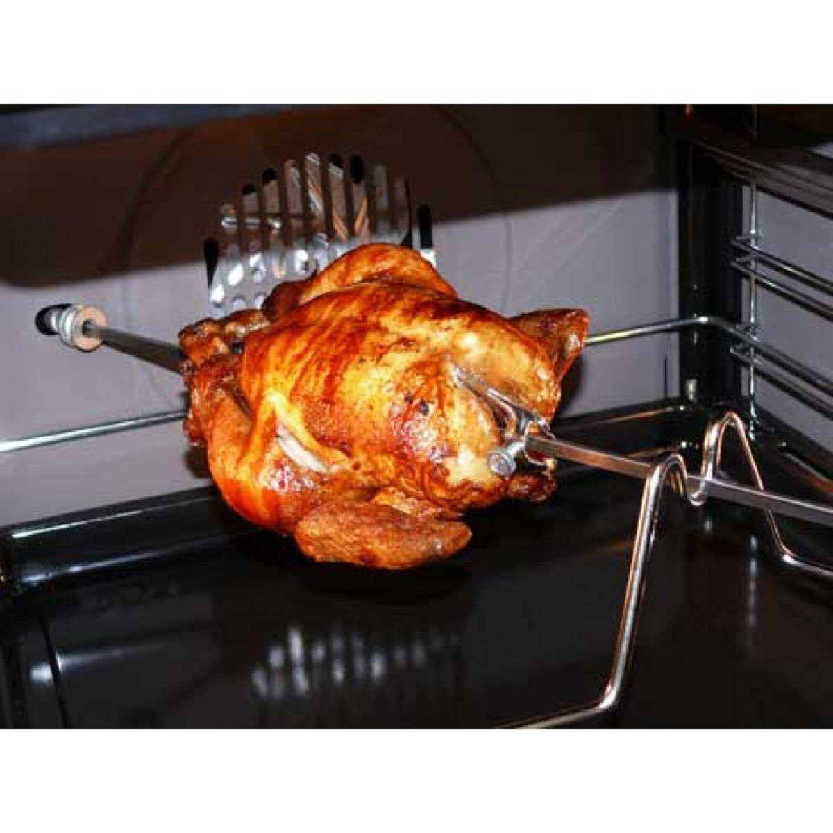 Ein gebratenes Hähnchen am Drehspieß im Ofen. Das Hähnchen ist goldbraun, der Ofeninnenraum ist dunkel.