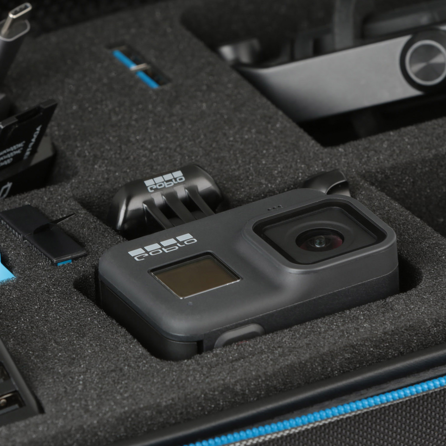 Schwarze GoPro-Kamera und Zubehör in einem schaumstoffgefütterten Koffer. Kamera mittig.