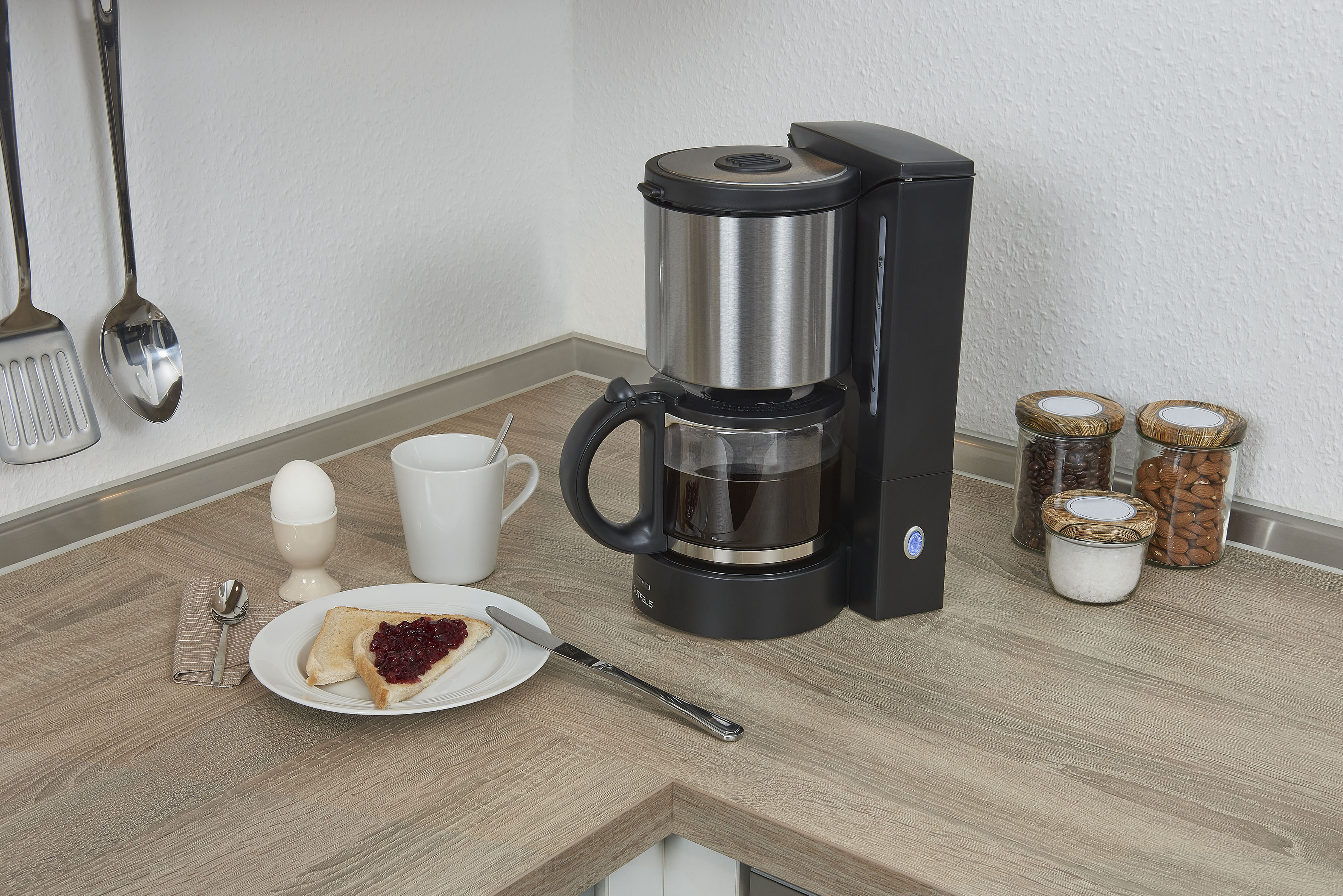Kaffeemaschine mit Kaffee, Toast mit Marmelade und andere Frühstücksartikel auf einer Theke.
