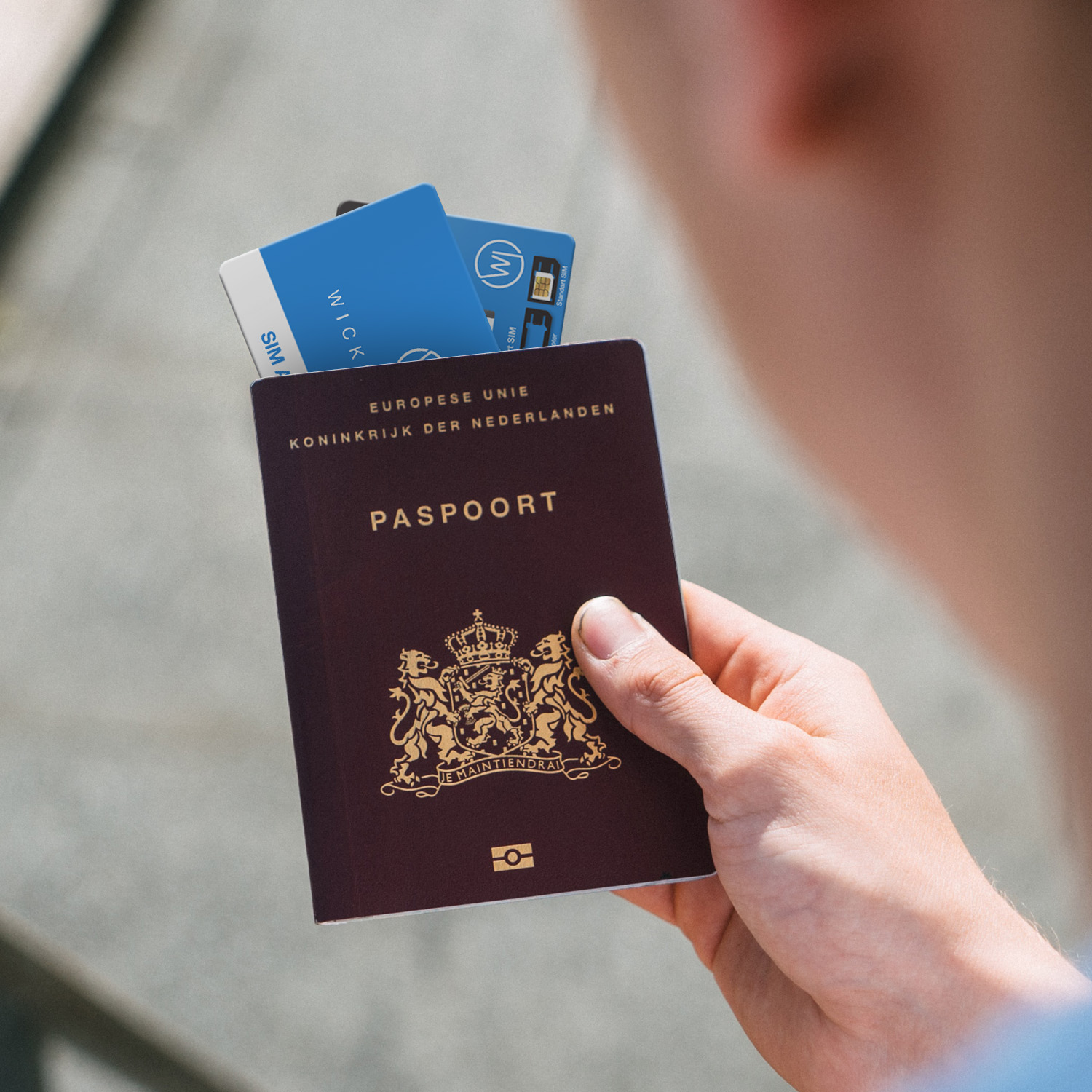 Hand, die einen Reisepass mit Karten darin hält, vor verschwommenem Hintergrund.