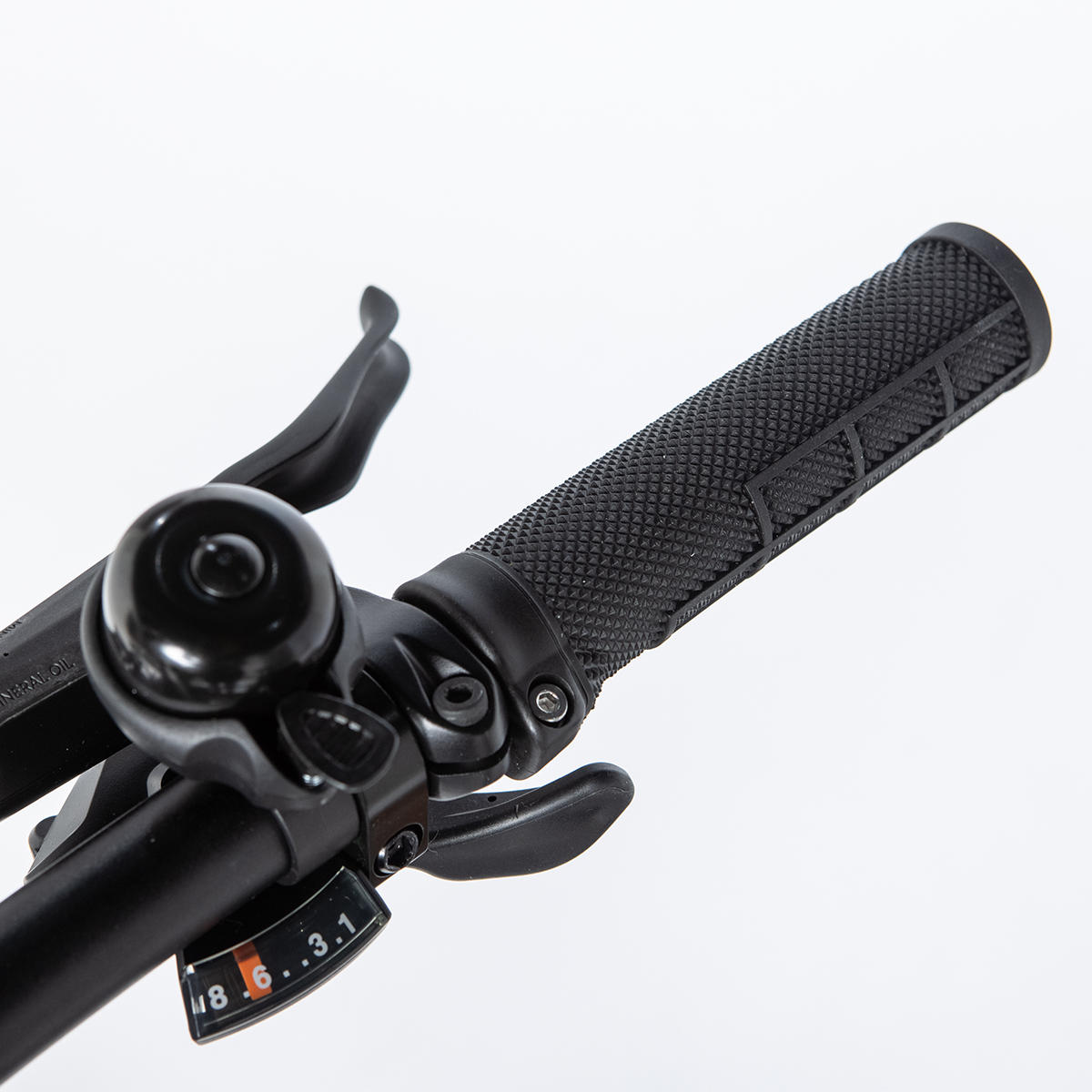 Primer plano del manillar de bicicleta. Negro, con cambios, timbre y puños.