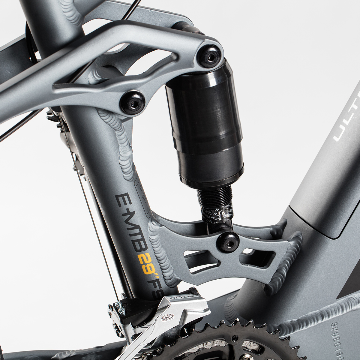 Nahaufnahme eines grauen Fahrradrahmens mit den Worten E-MTB 29 FE. Ein schwarzes Federungssystem ist sichtbar.