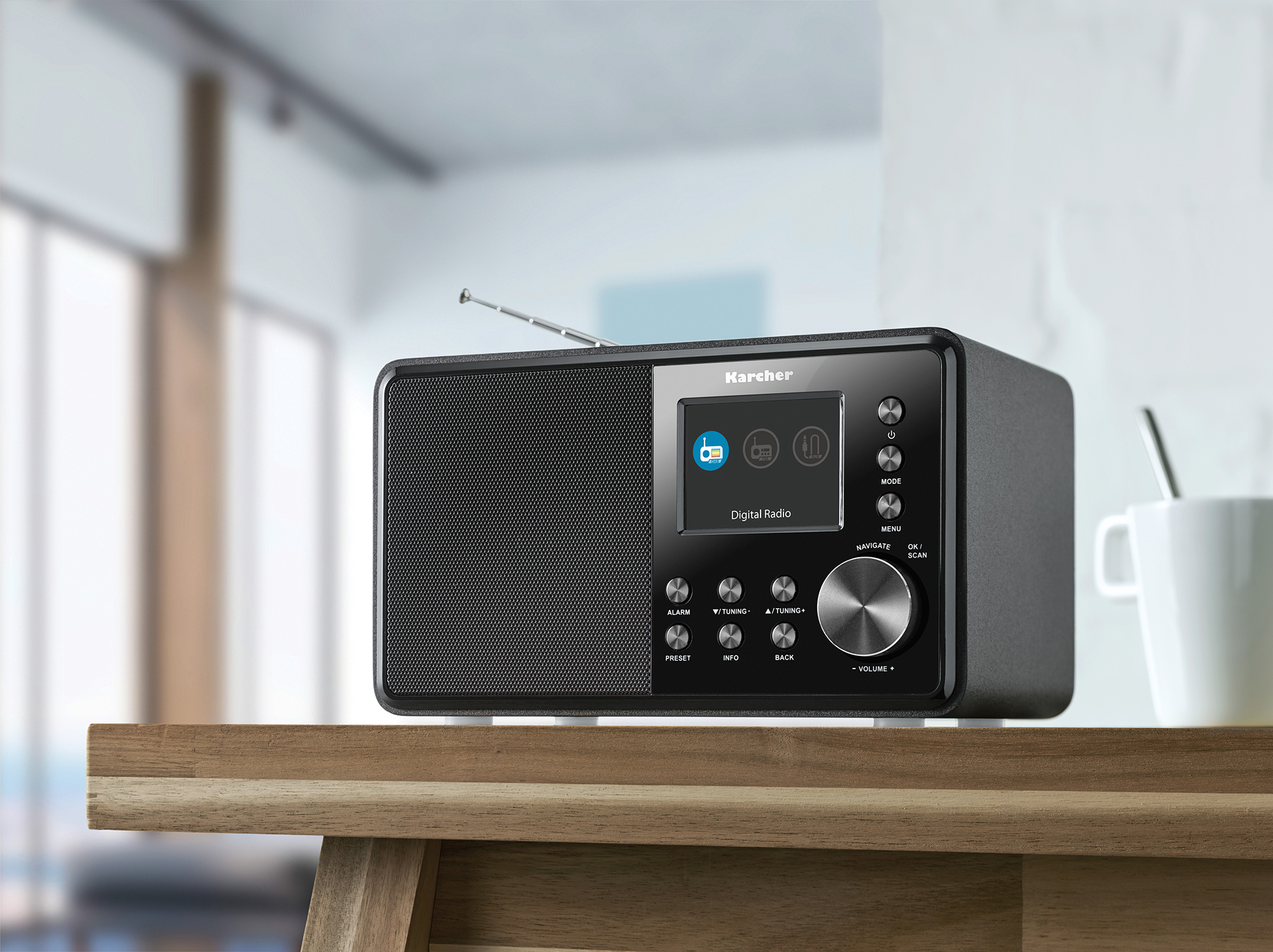 Radio noire sur une table en bois. La radio a un écran et des boutons. L'arrière-plan est flou.