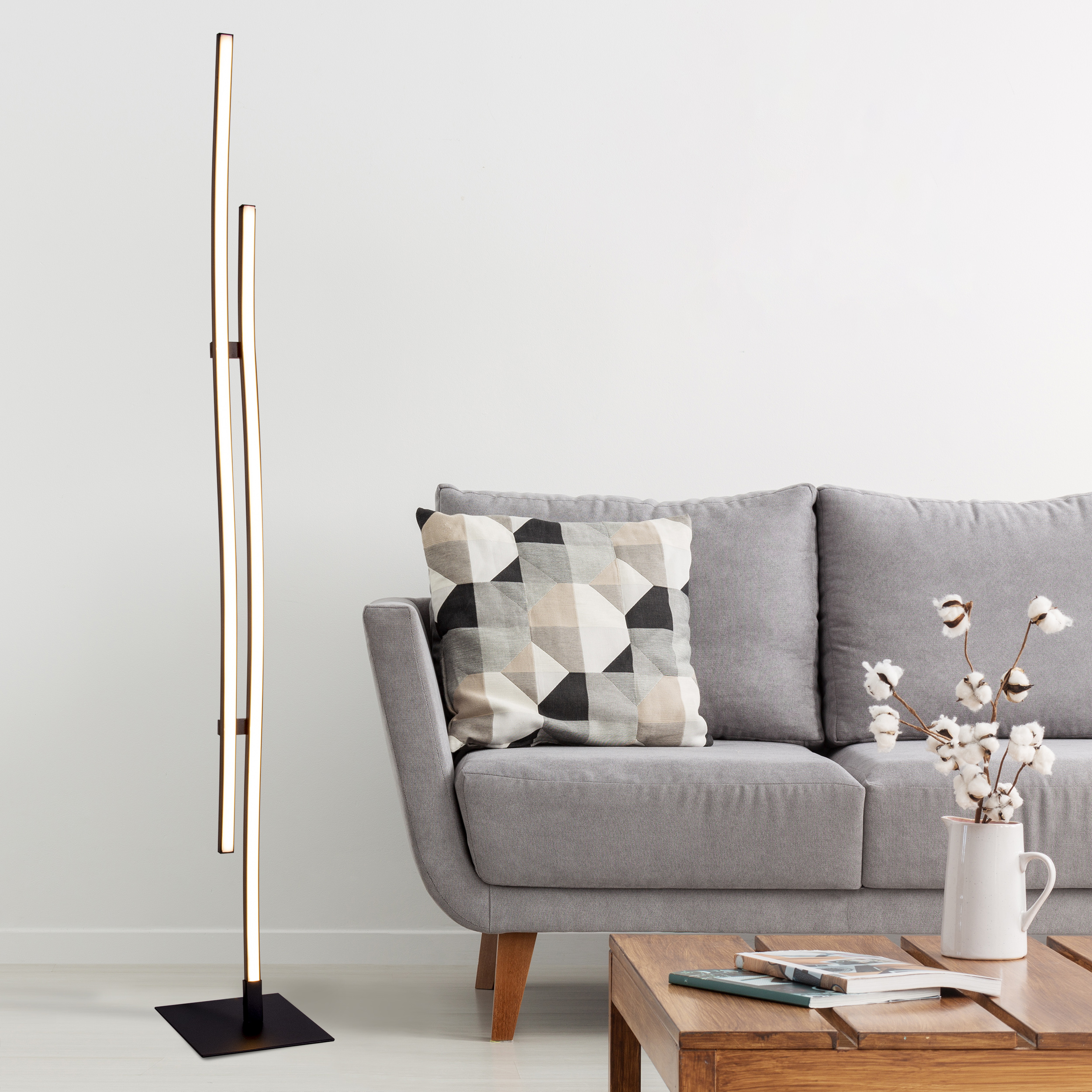 Eine moderne Lampe mit weißem Hintergrund, einem grauen Sofa und einem Holztisch.