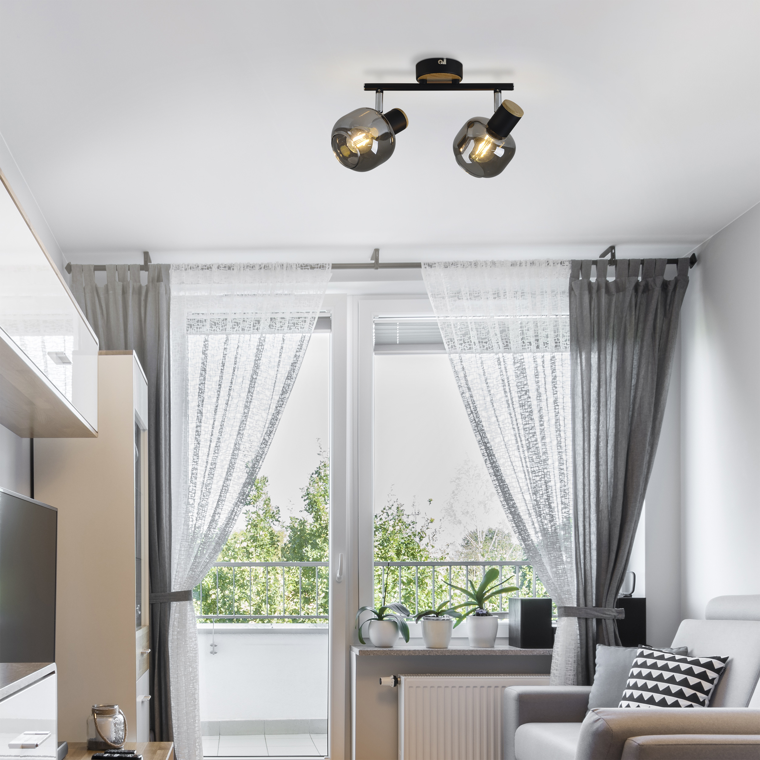 Modernes Wohnzimmer mit Sofa, Vorhängen und Deckenleuchte.