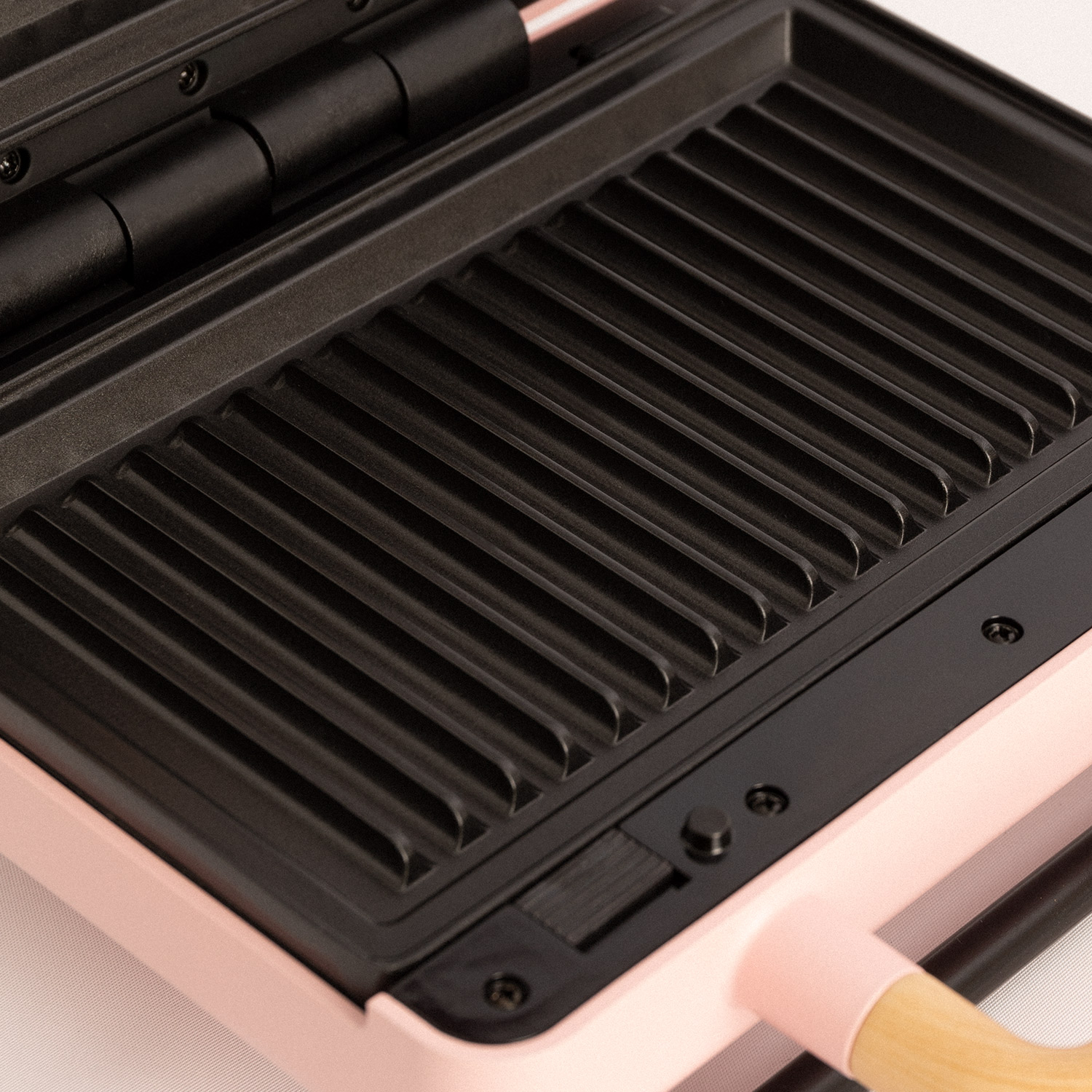 Primer plano de una plancha para gofres rosa y negra, mostrando la parrilla.