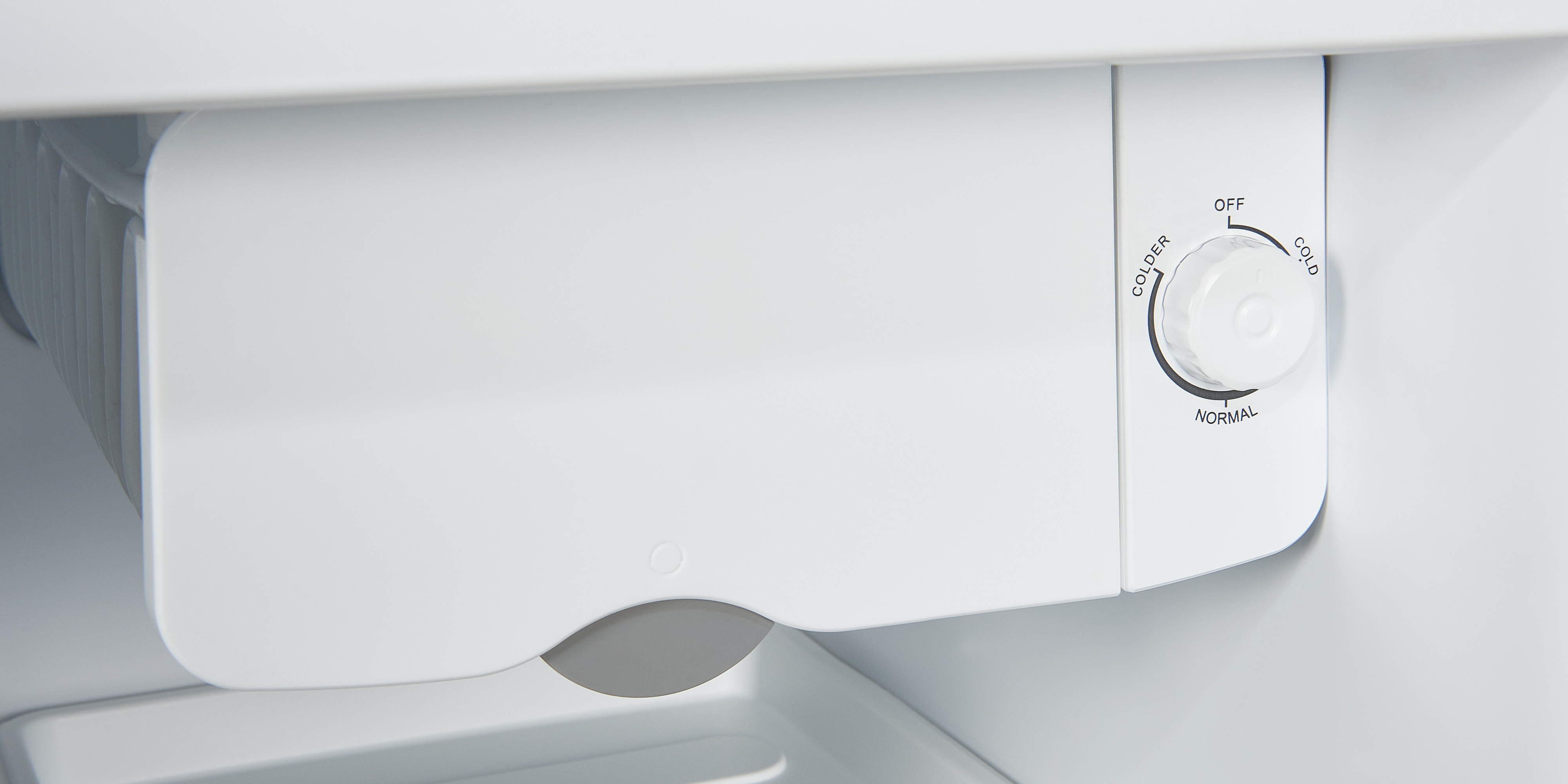 Primer plano de un componente de refrigerador blanco. Tiene un dial de control de temperatura.