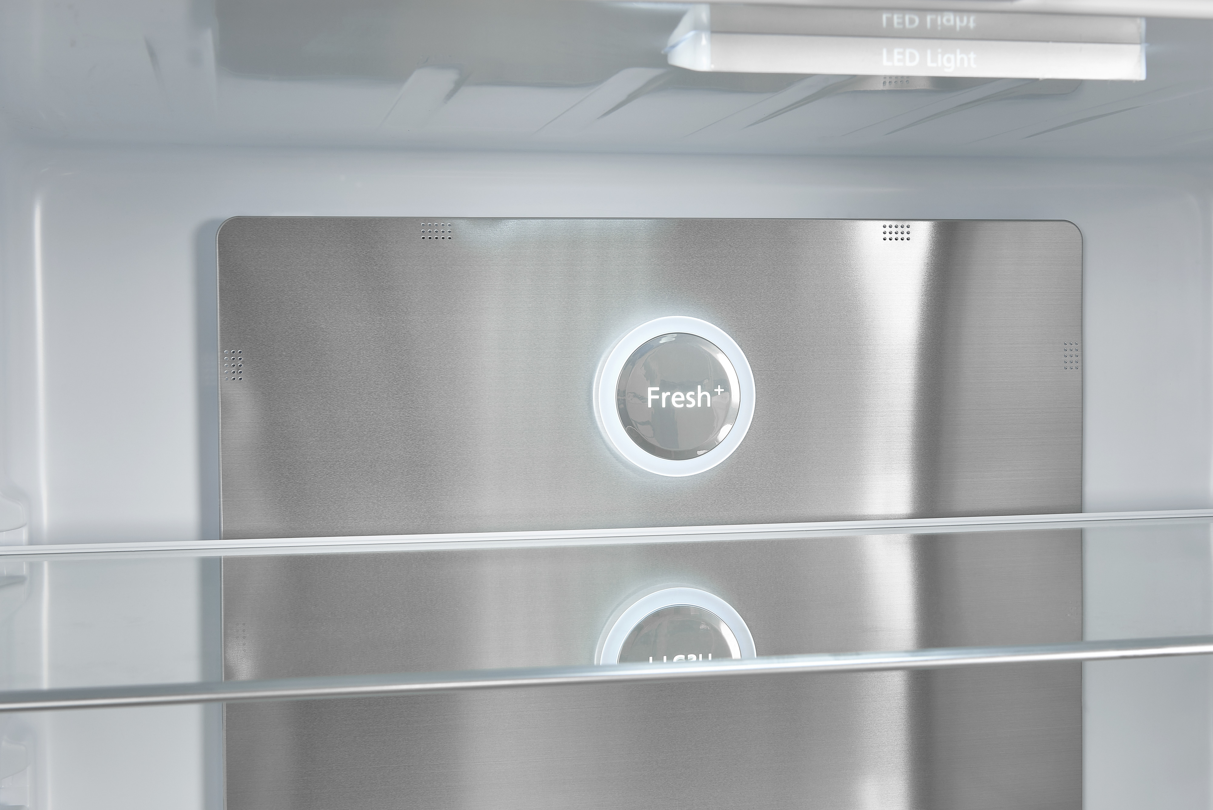 Im Inneren eines Kühlschranks. Eine silberne Platte mit Fresh+-Taste und zwei Glasböden sind sichtbar.