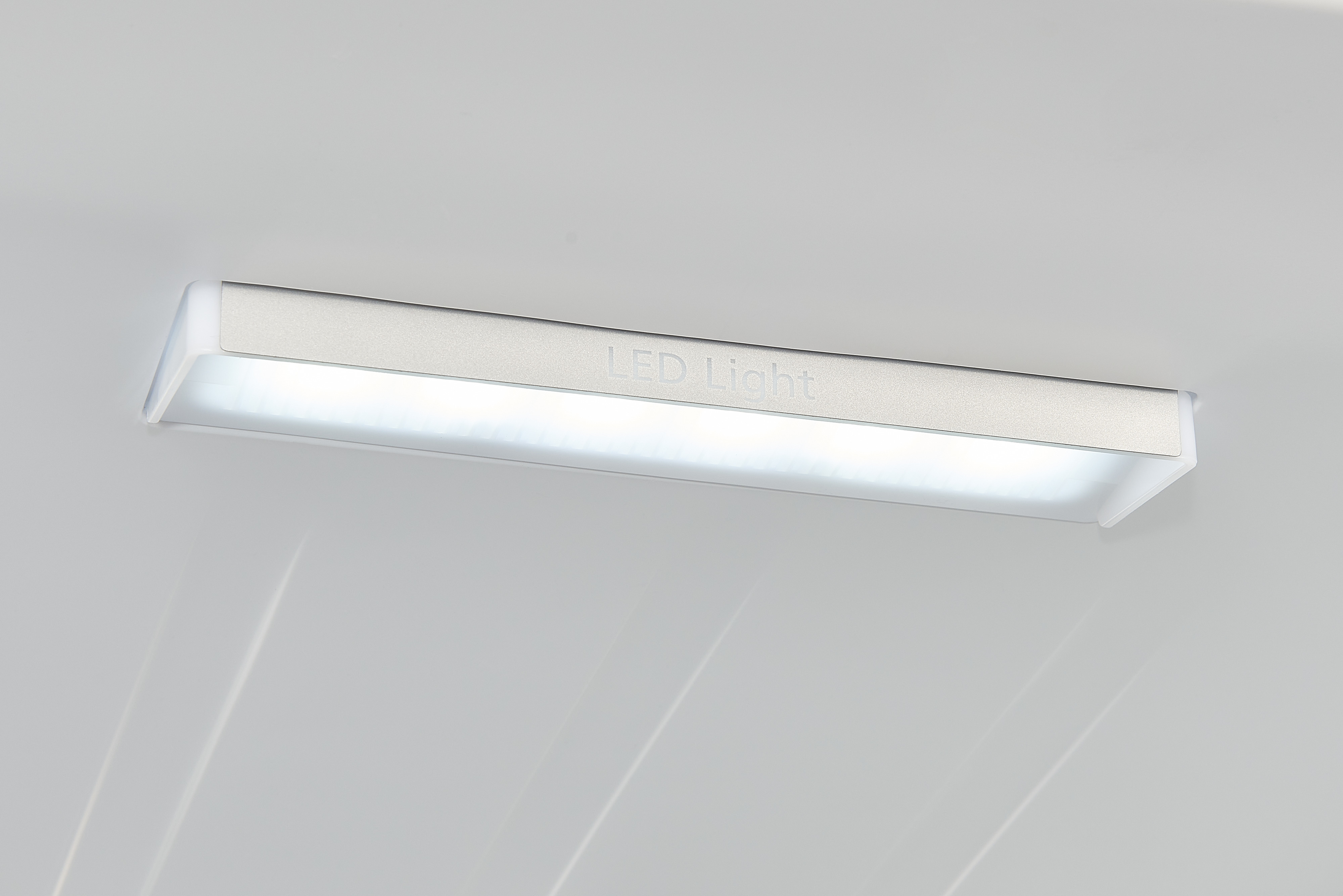 Eine rechteckige LED-Leuchte, die auf einer weißen Oberfläche montiert ist und leuchtet.