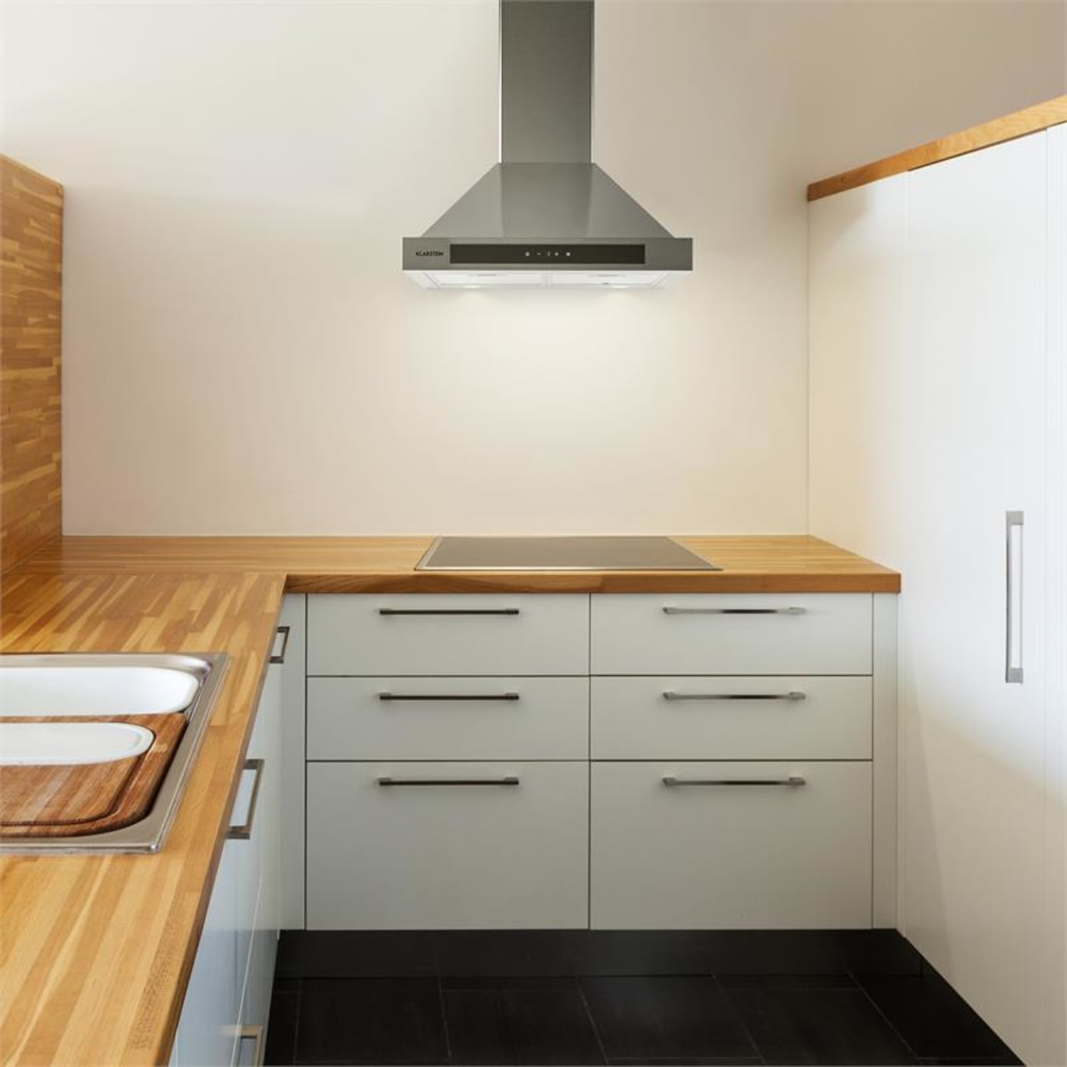 Una cocina con encimeras de madera, gabinetes blancos y una campana extractora de acero inoxidable.