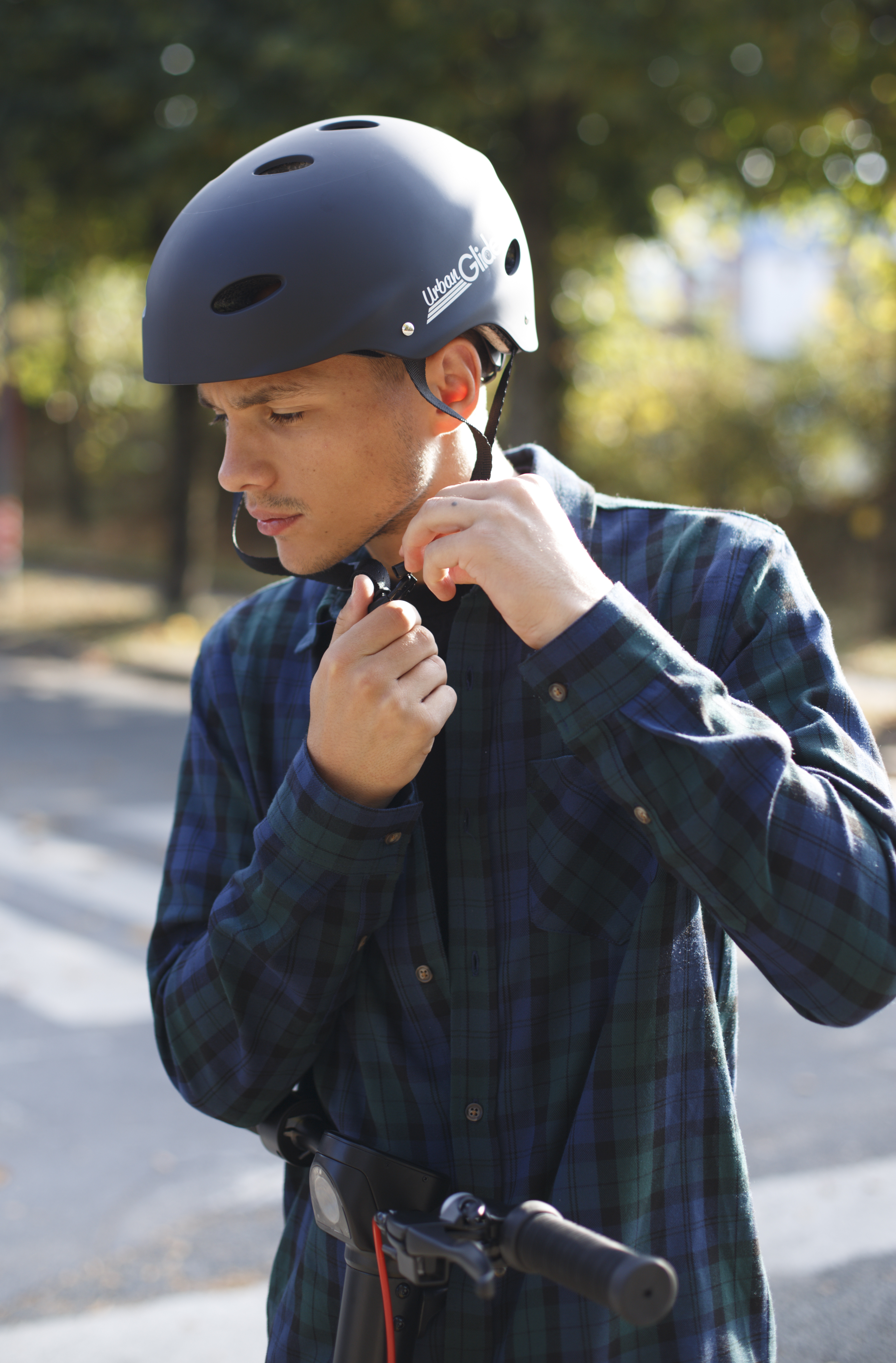 Un hombre con casco ajustando una correa. Lleva una camisa a cuadros.