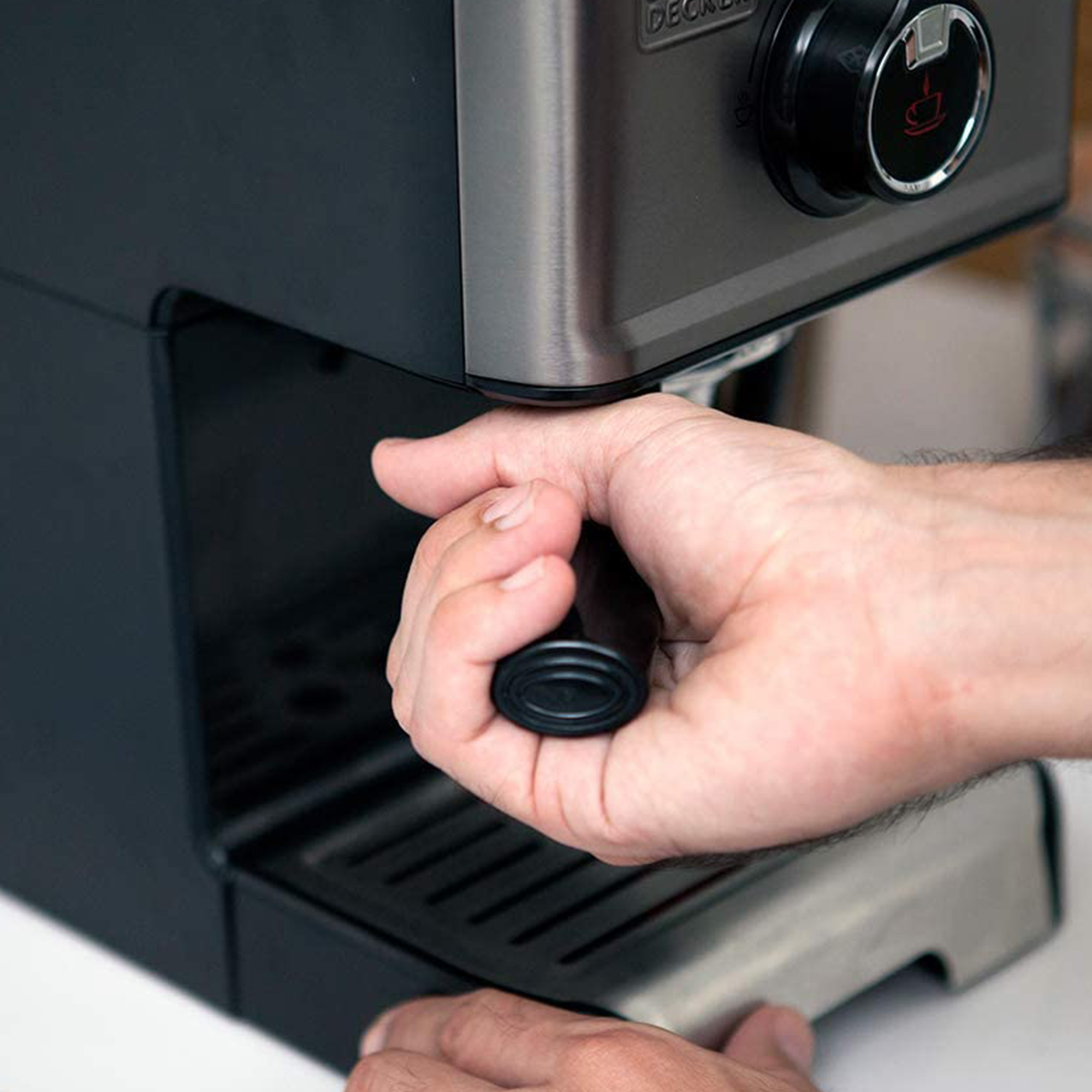 Dłoń trzymająca uchwyt ekspresu do kawy, zbliżenie, czarne detale.