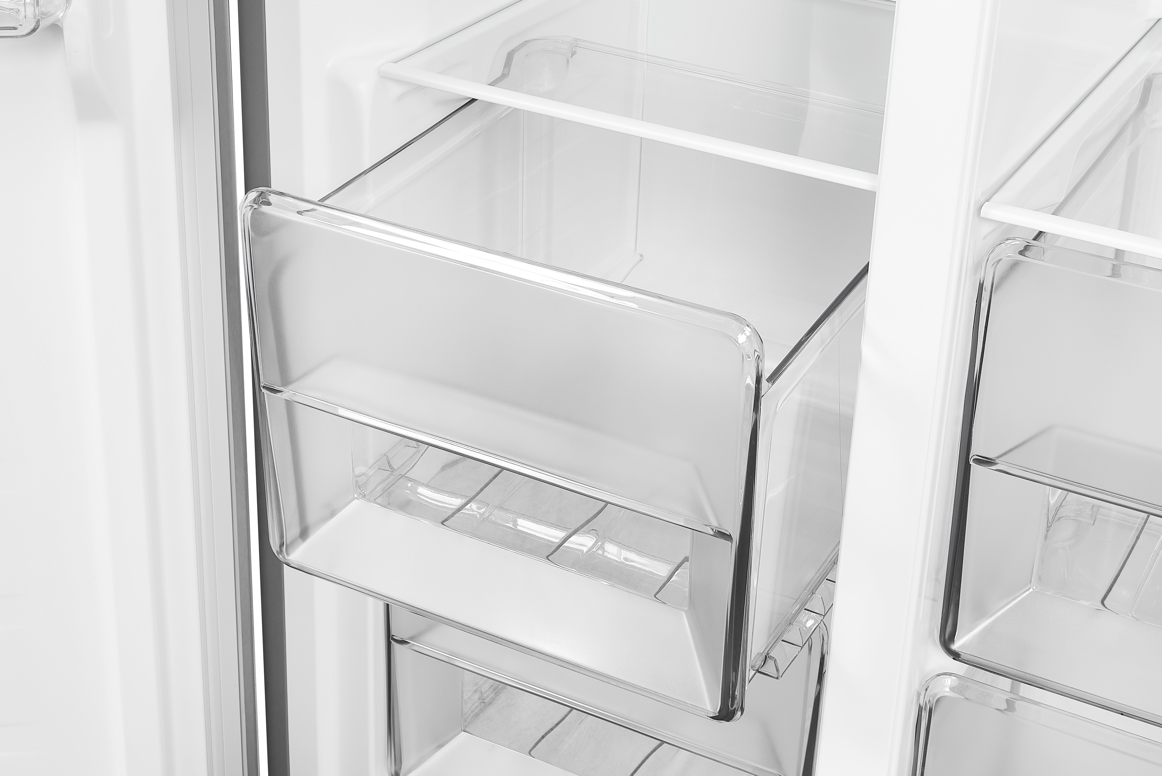 Ein weißer Kühlschrank mit einer transparenten, offenen Schublade, die Innenregale zeigt.