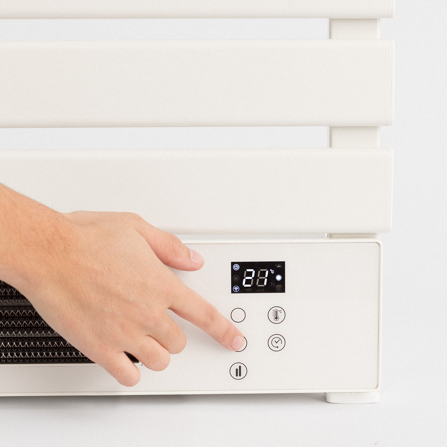 Una mano presiona un botón en un panel de control digital blanco de un calentador.
