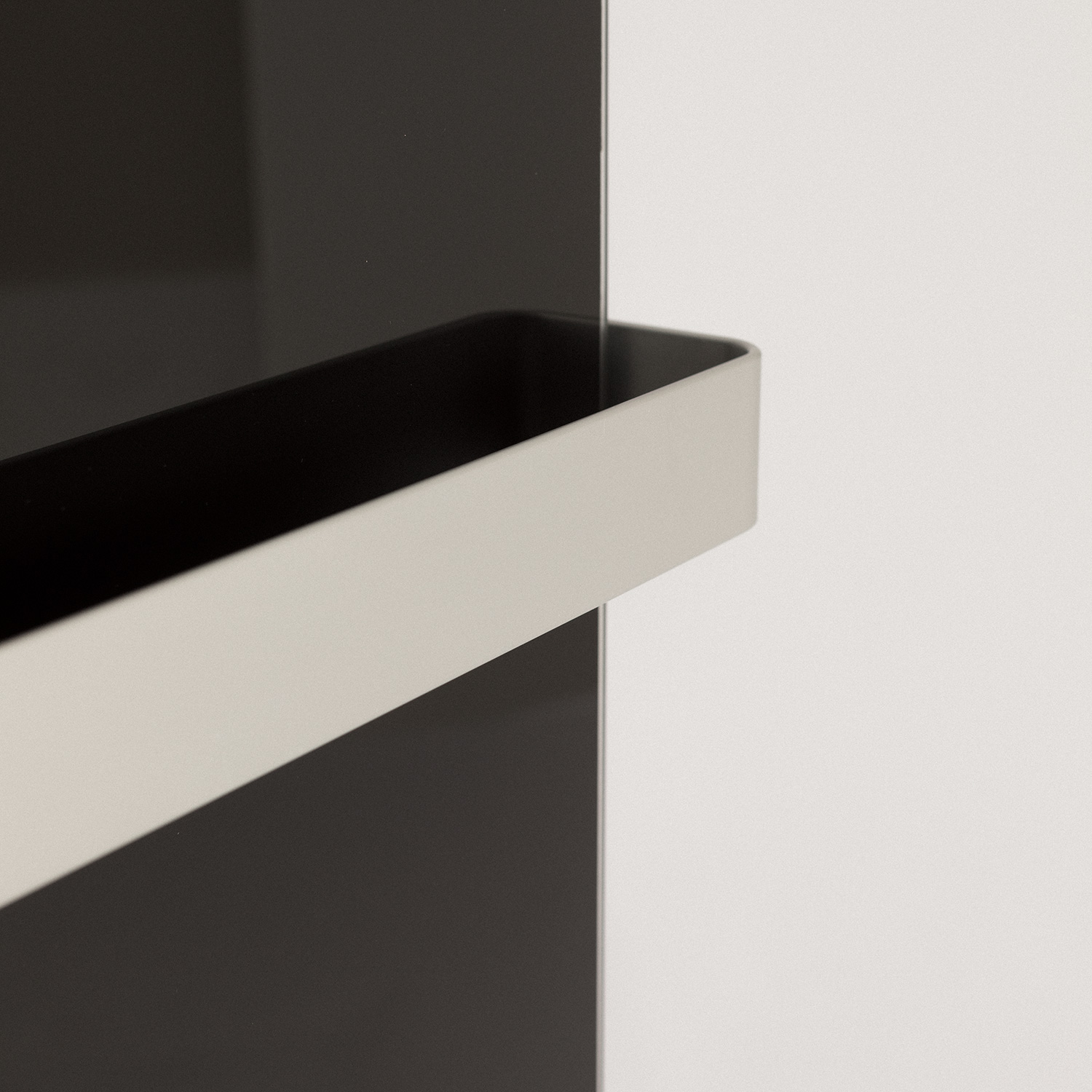Manija de metal gris en un panel negro, contra una pared blanca.