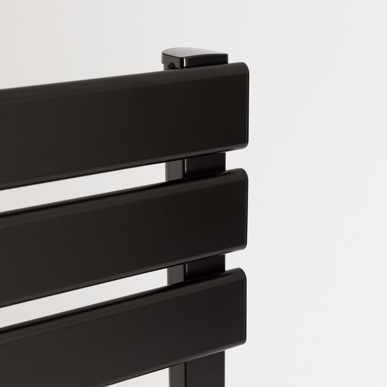 Primer plano de un radiador negro horizontal. La parte superior tiene una pequeña tapa negra.