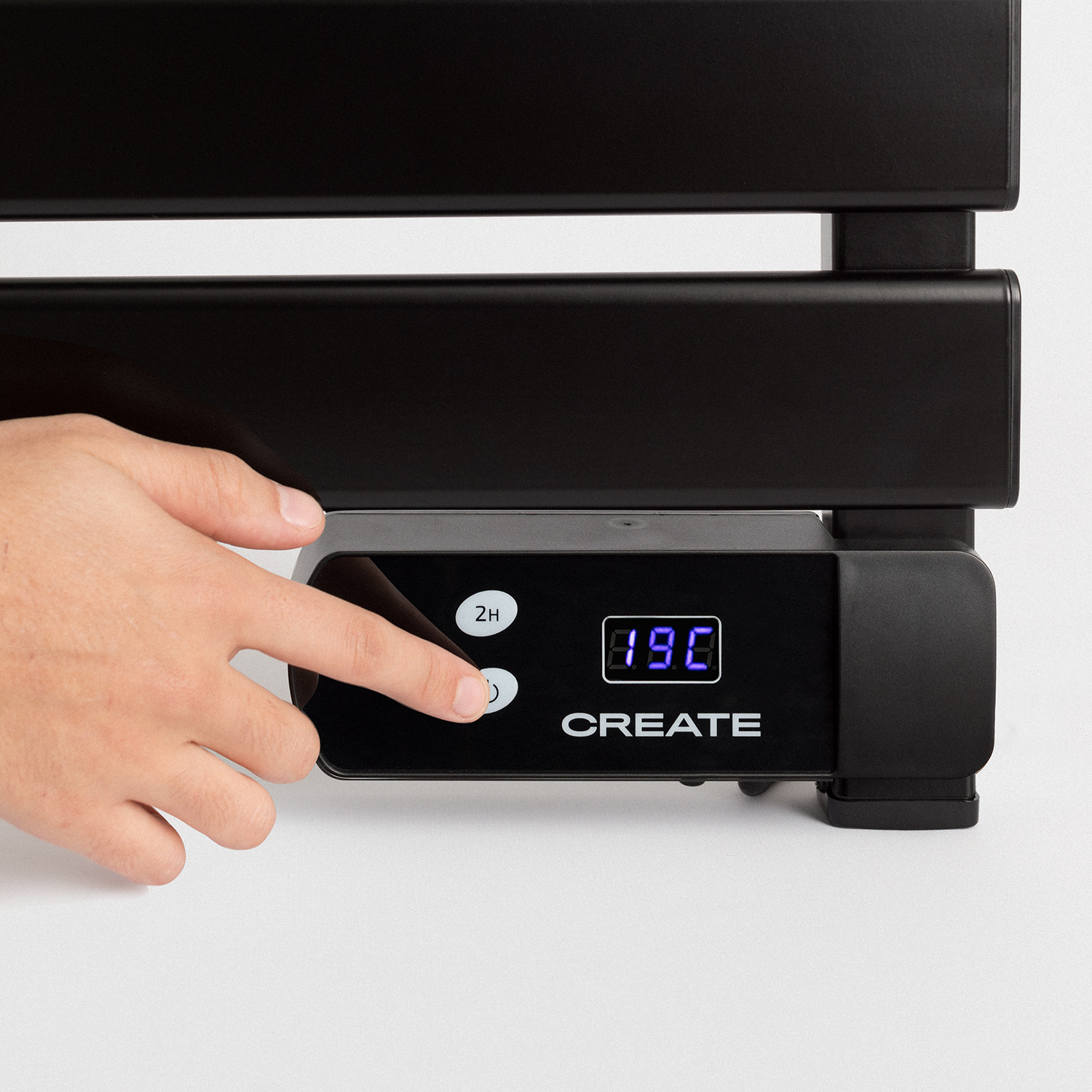 Radiador negro con pantalla digital que muestra 19°C. Una mano lo toca.