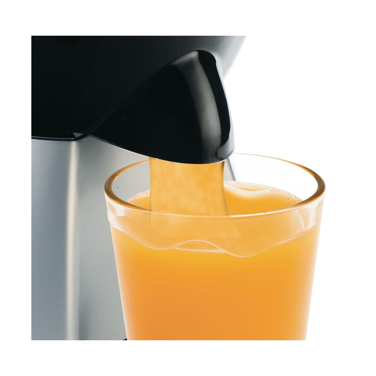 Jugo fluyendo de una exprimidora negra a un vaso. El jugo es naranja y el vaso es transparente.