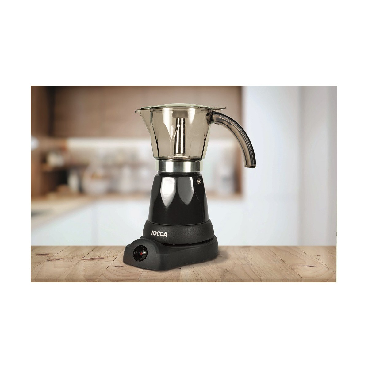 Cafetera negra sobre mesa de madera frente a cocina borrosa.