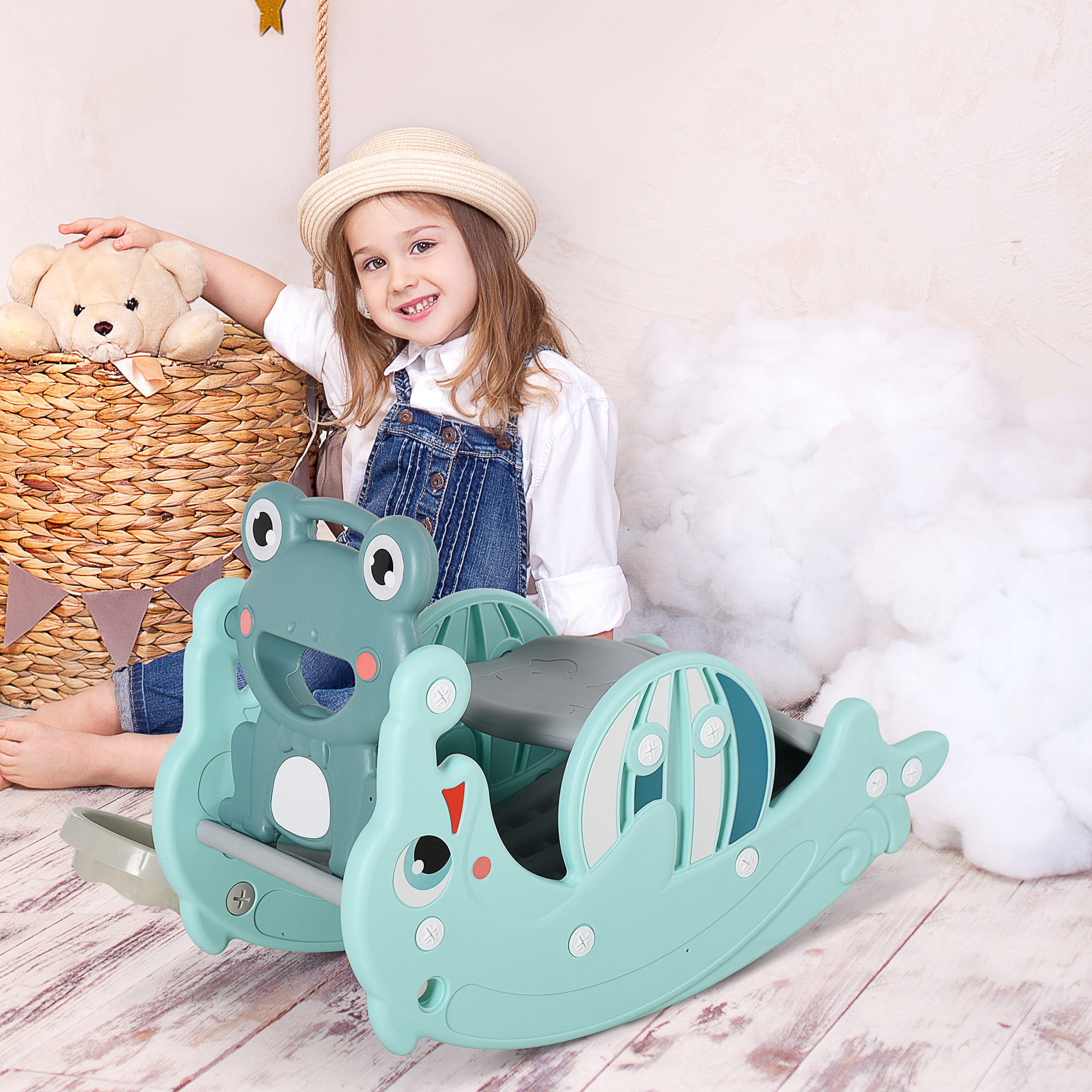 Bambina con giocattolo e orsacchiotto. Giocattolo a dondolo verde e blu. Sfondo bianco.