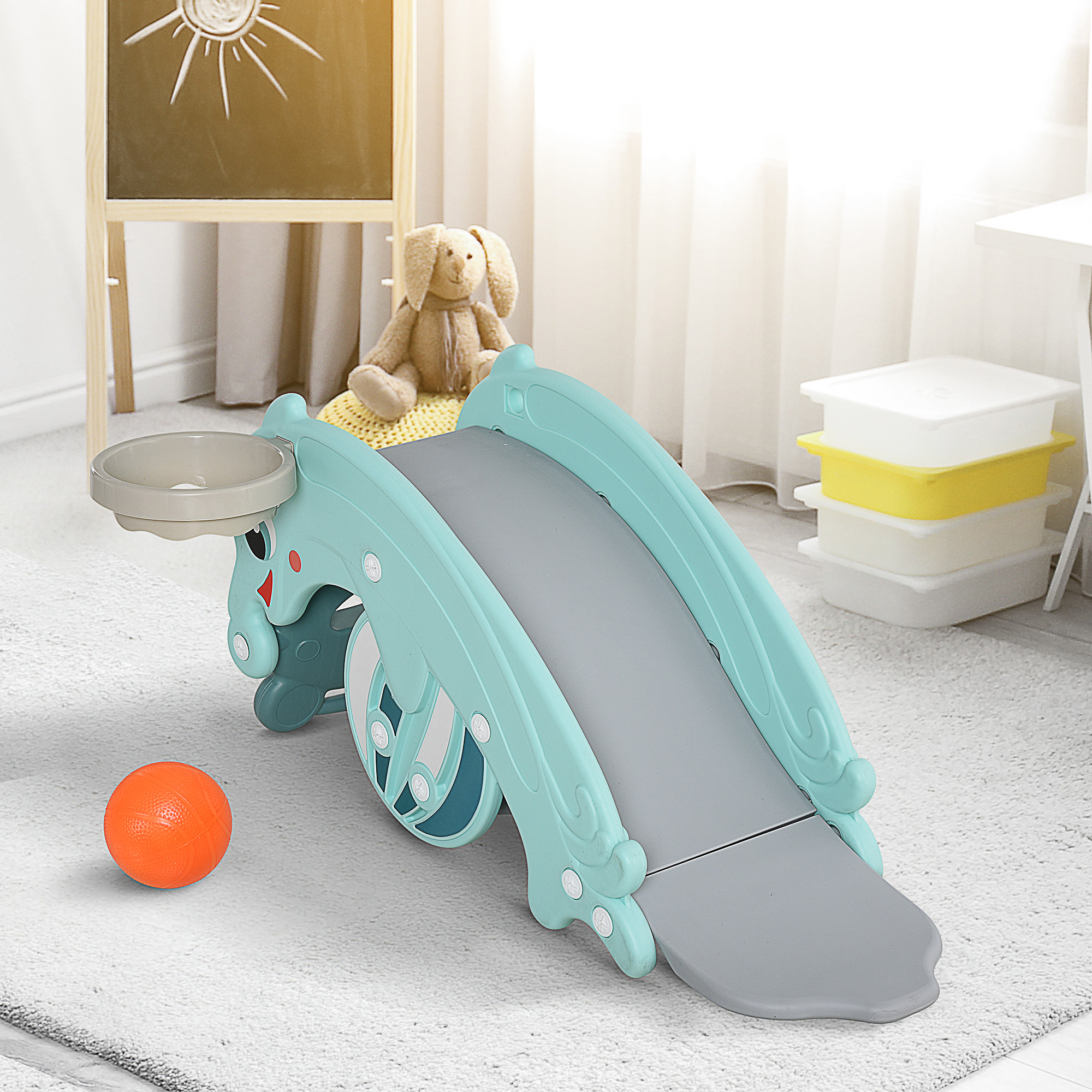 Uno scivolo blu con canestro da basket e palla arancione su un tappeto bianco.