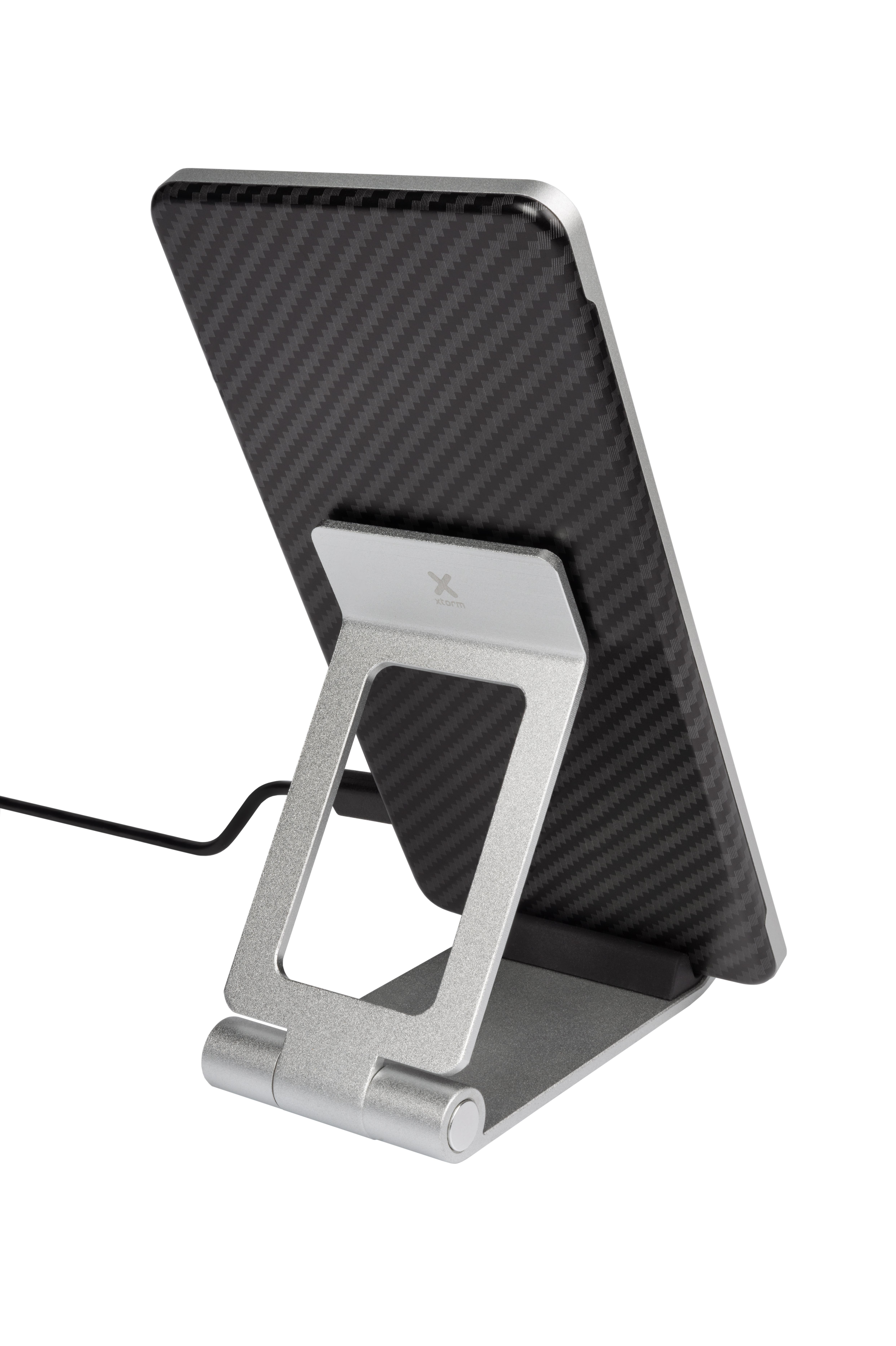 Tablet auf einem silbernen Ständer, mit schwarzer Carbonfaser-Rückseite und Ladekabel.