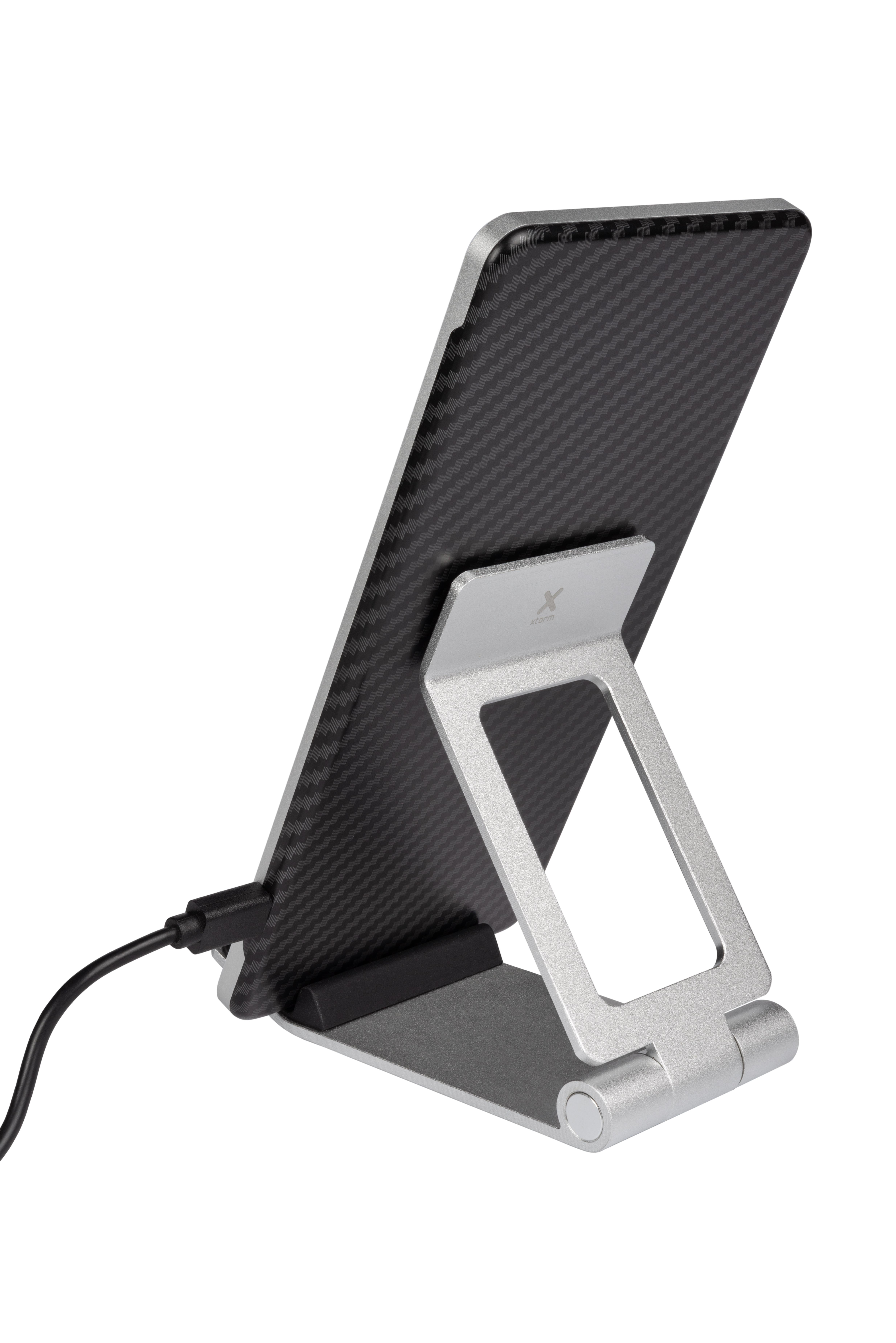 Tablet auf silbernem Ständer mit schwarzer Carbonfaser-Rückseite, verbunden mit Ladekabel.