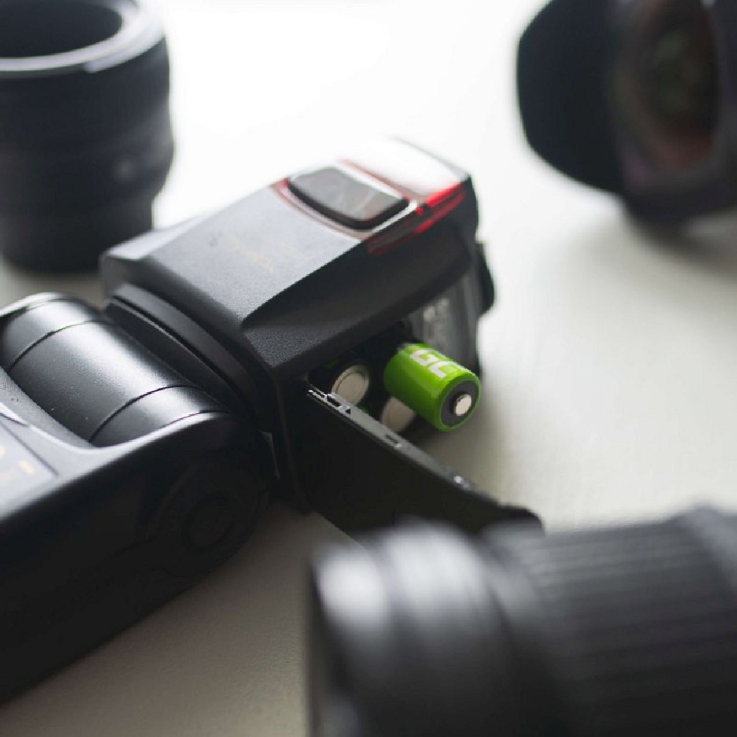 Flash della fotocamera con una batteria AA verde nel vano batterie.