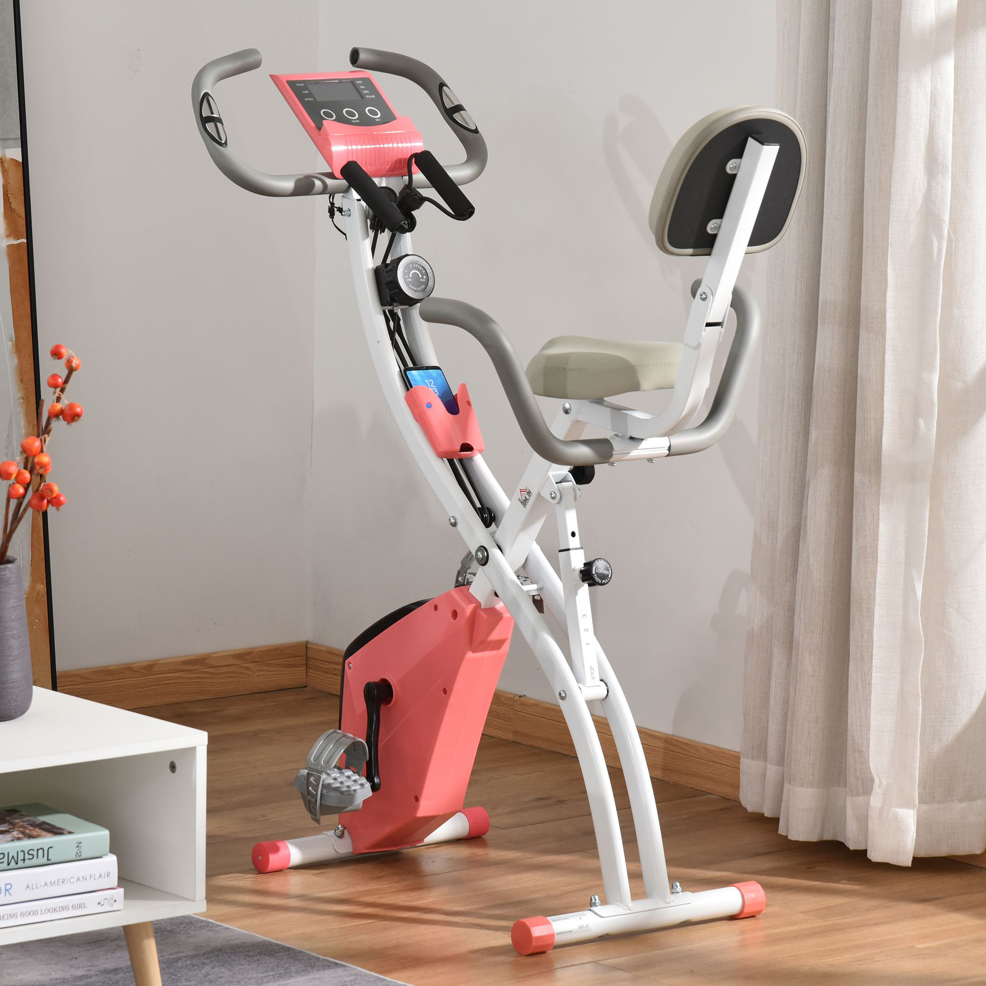 Rosa-weißes Trainingsfahrrad im Raum. Weißer Schrank und Fenster im Hintergrund.