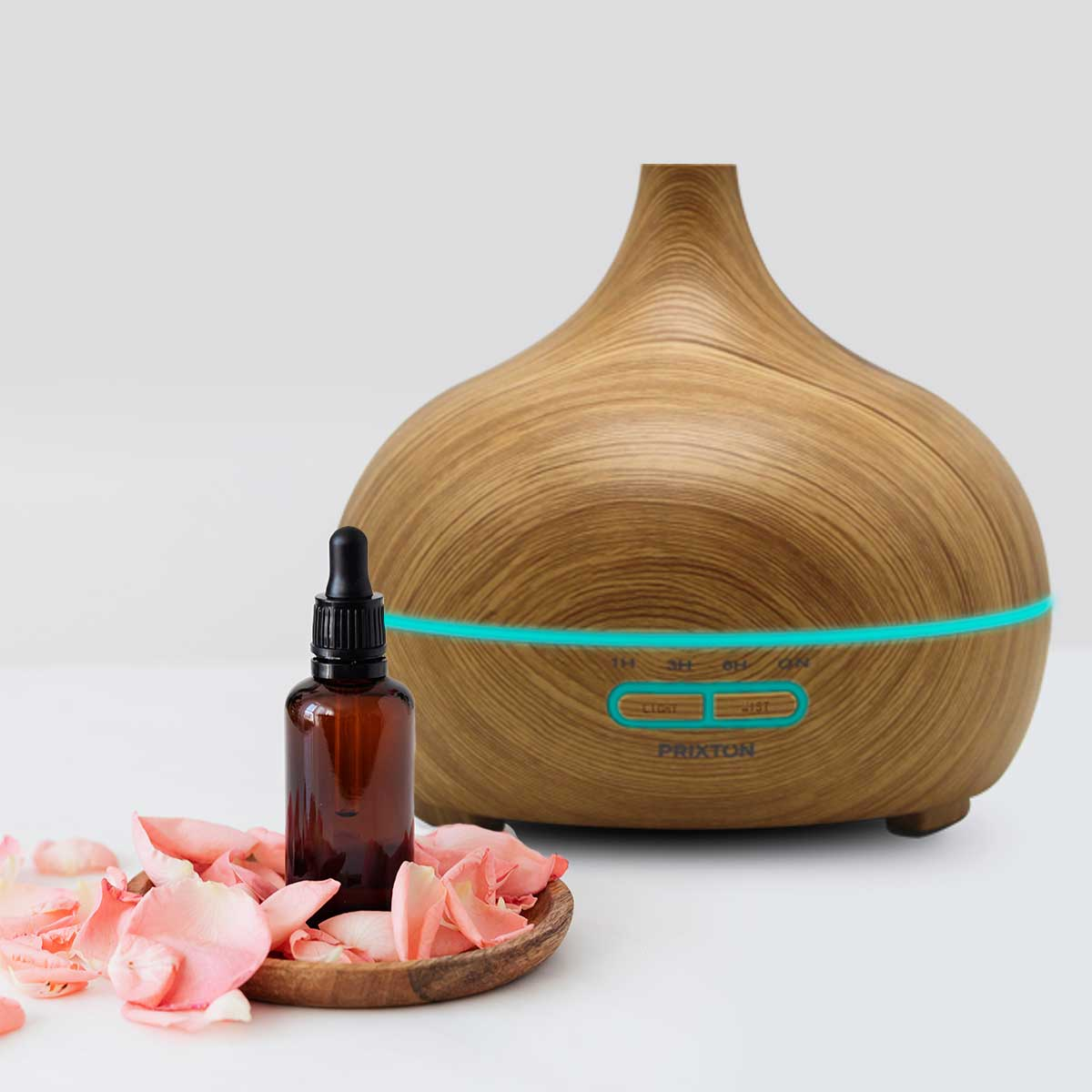 Drewniany dyfuzor zapachów, butelka oleju i płatki róż na białej powierzchni.